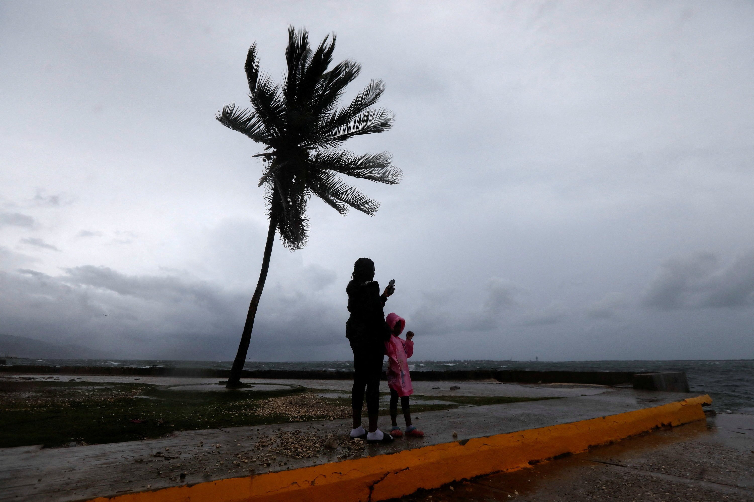 A woman and a child stand along the Kingston waterfront as Hurricane Melissa approaches, in Kingston, Jamaica on Monday. Photo: Reuters