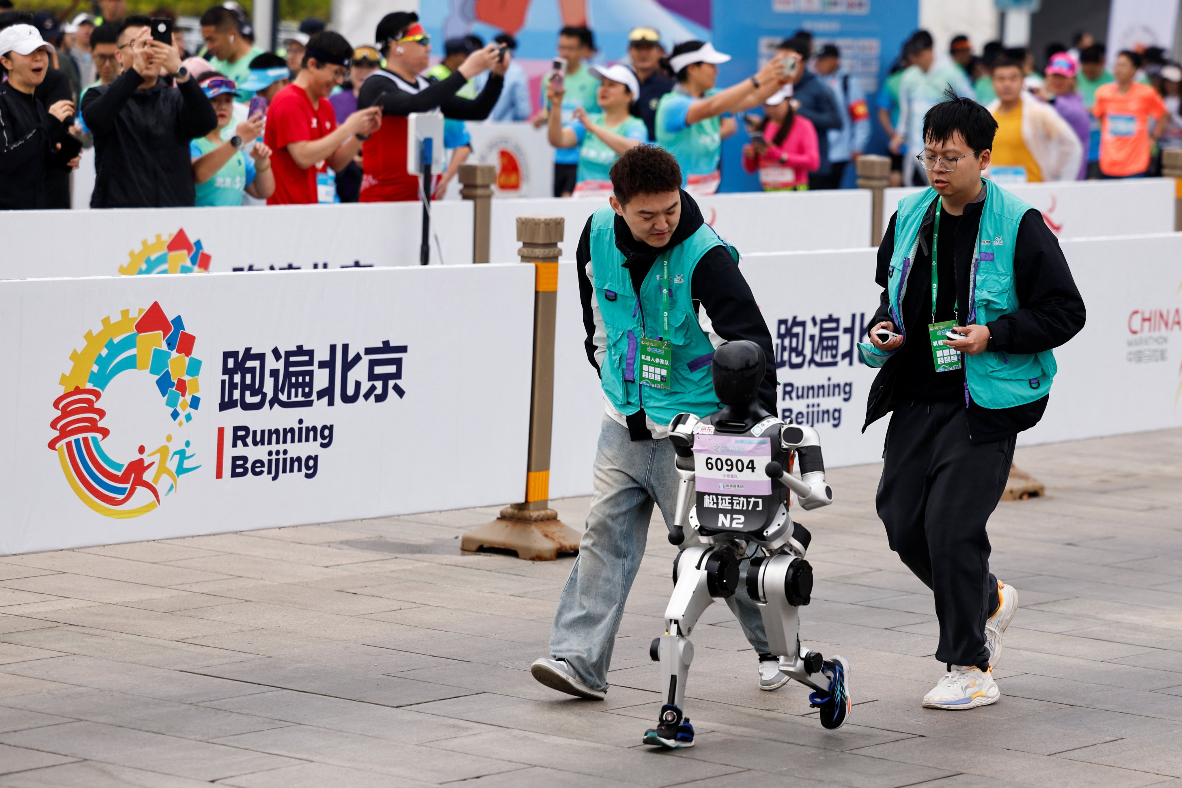 Engineers run with a robot taking part in a half marathon race in Beijing, on April 19. Photo: Reuters