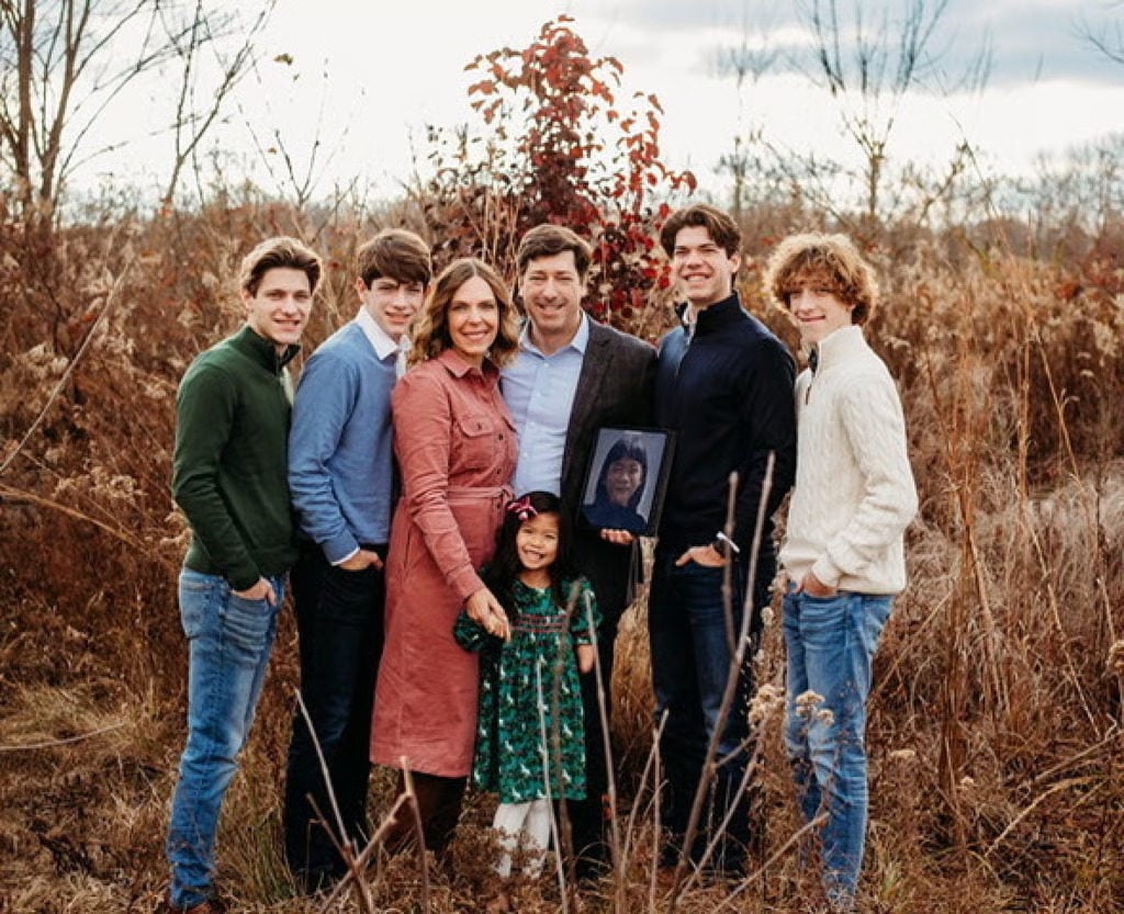 Aimee and Stephen Welch hold a photo of the girl they hope to adopt and name Penelope. They are pictured with their family, including their daughter, Grace, who was adopted from China in 2017. Photo: Welch family