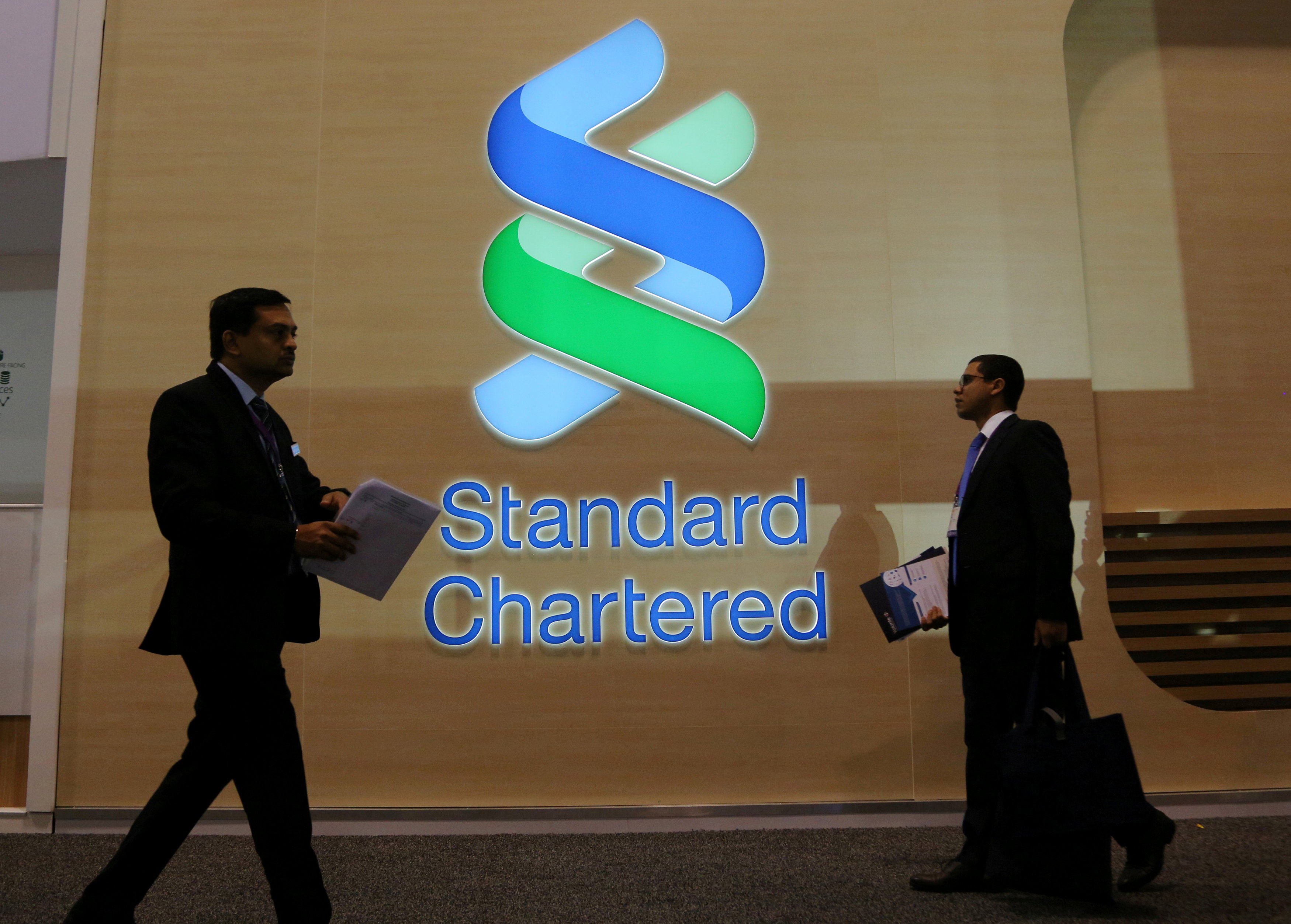People pass by the logo of Standard Chartered at a banking and financial conference in Toronto, Canada. File photo: Reuters