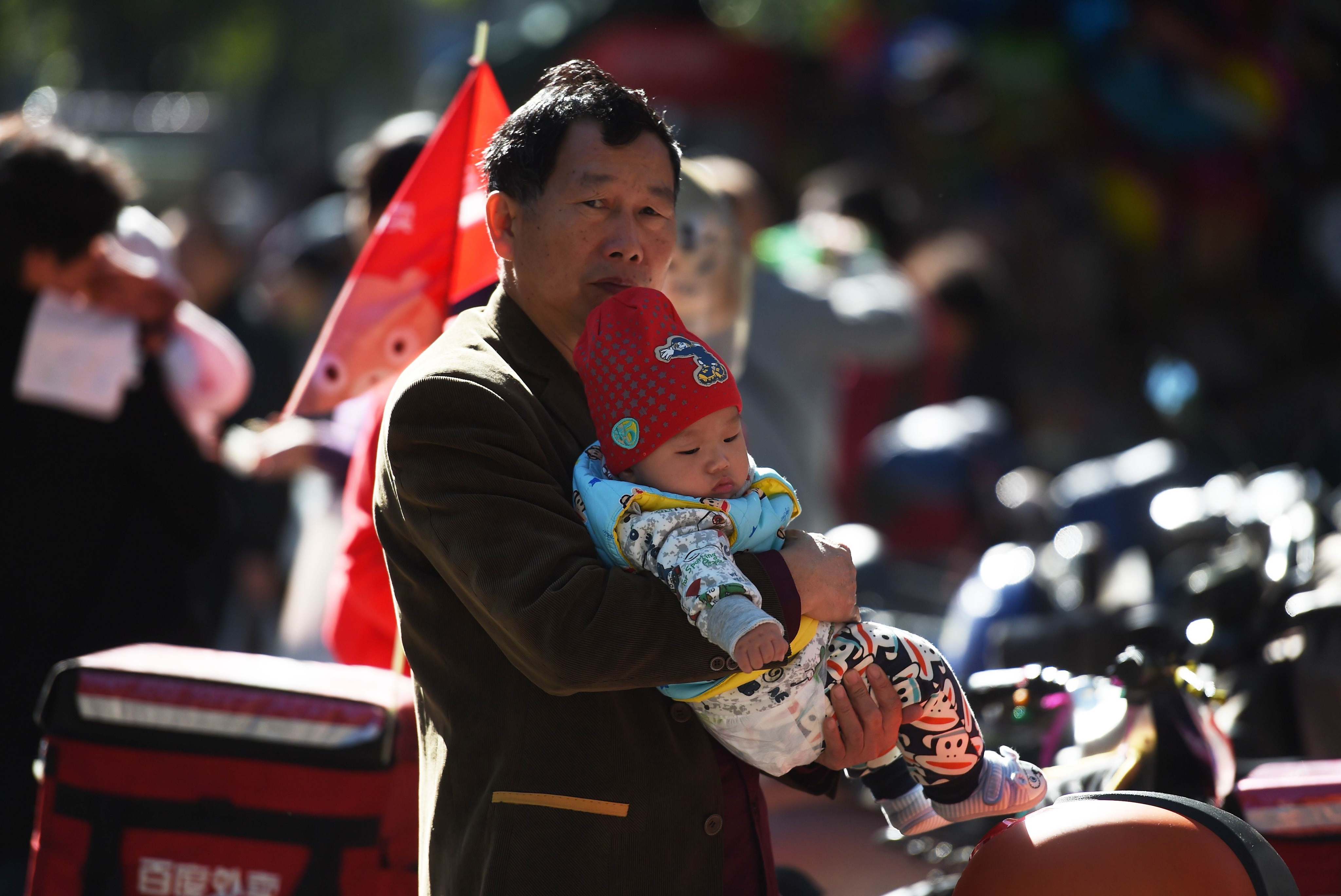 A man holds a baby on a path outside a children’s hospital in Beijing on October 30, 2015. Photo: AFP