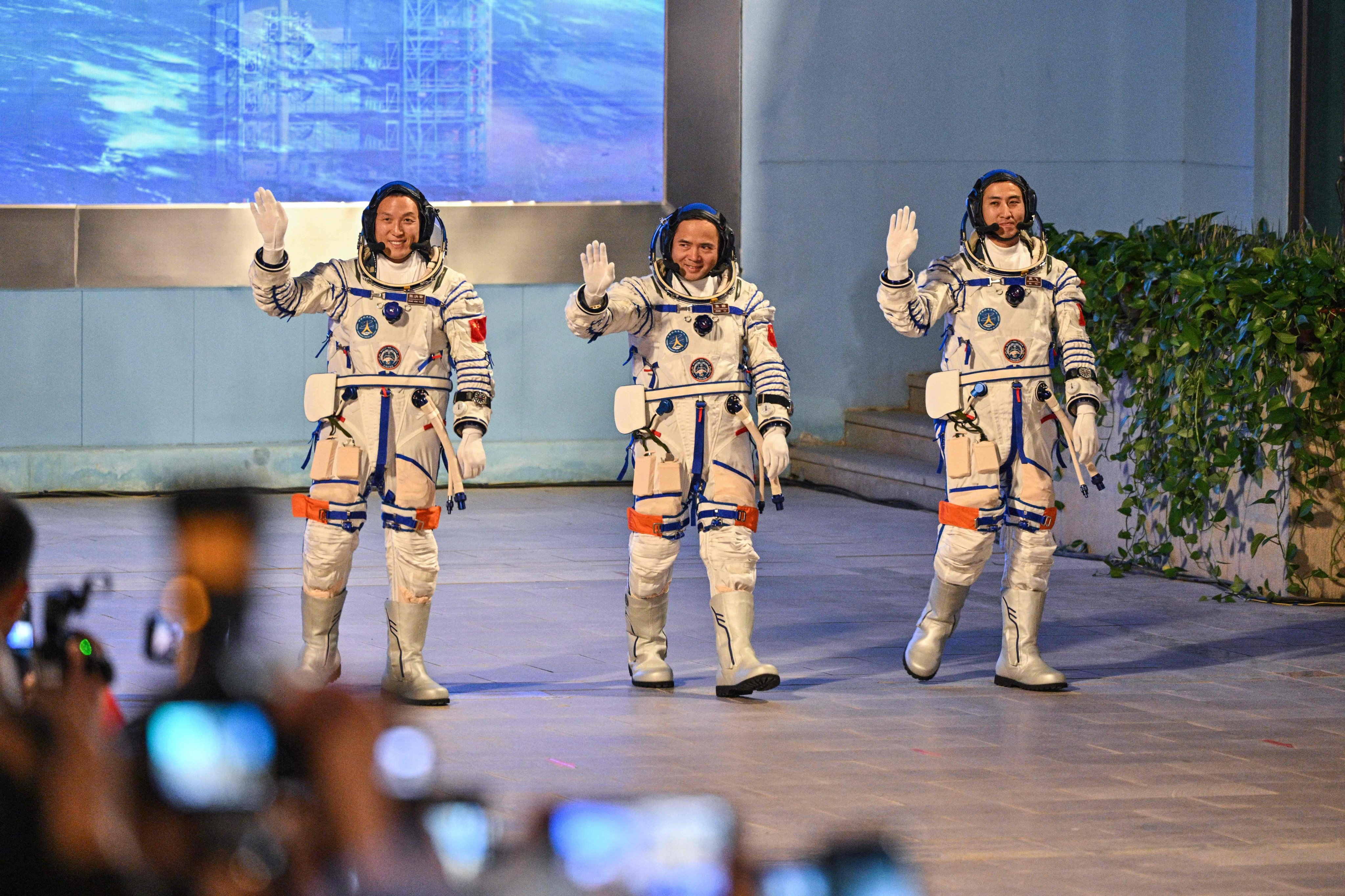 Shenzhou-21 crew members Zhang Hongzhang (left), Zhang Lu (centre) and Wu Fei (right) wave during a departure ceremony before boarding a bus to take them to the Jiuquan Satellite Launch Centre in northwest China on Friday. Photo: AFP