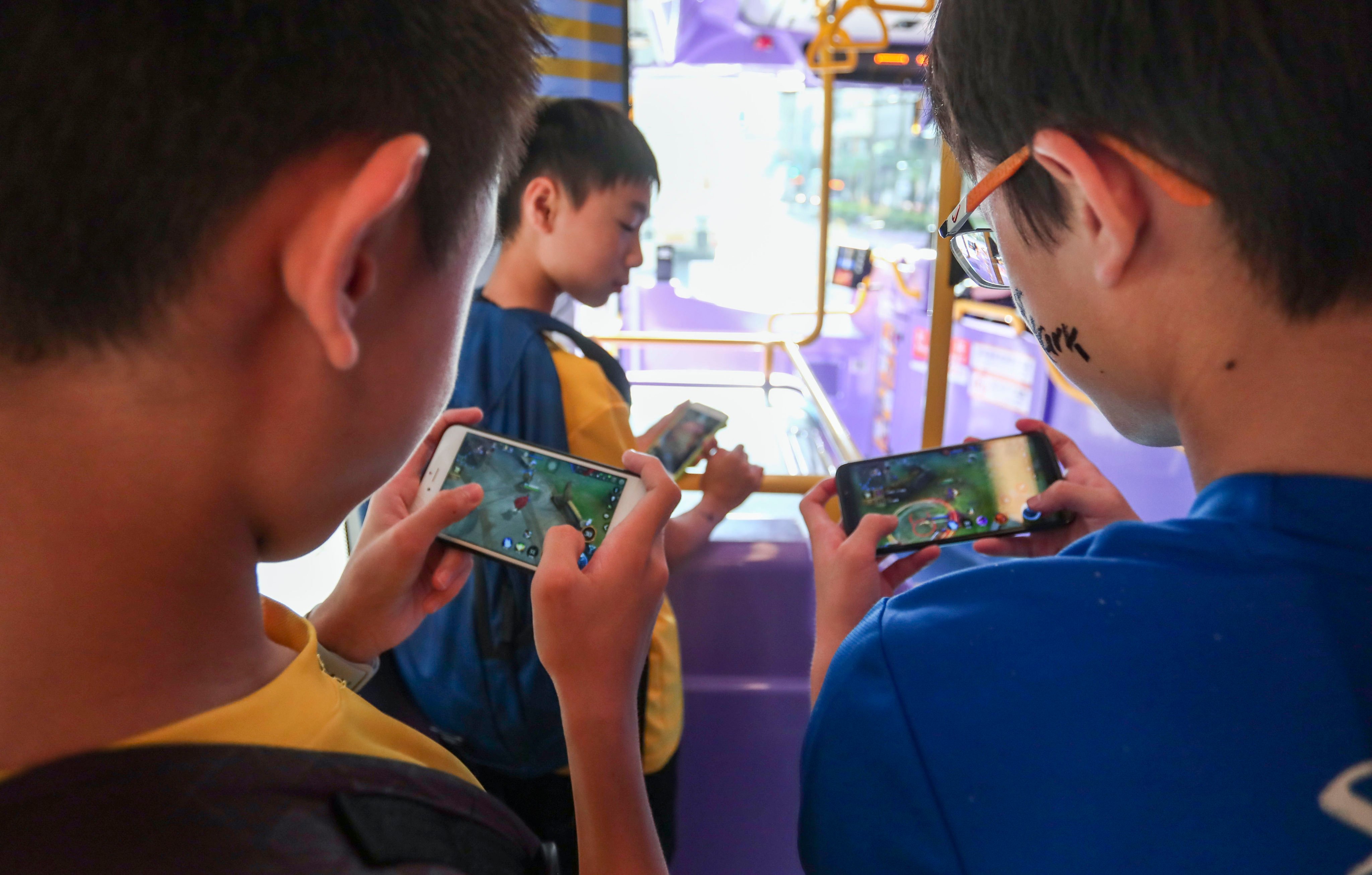 Boys play games on their smartphones on a bus in Hong Kong. Photo: Jonathan Wong