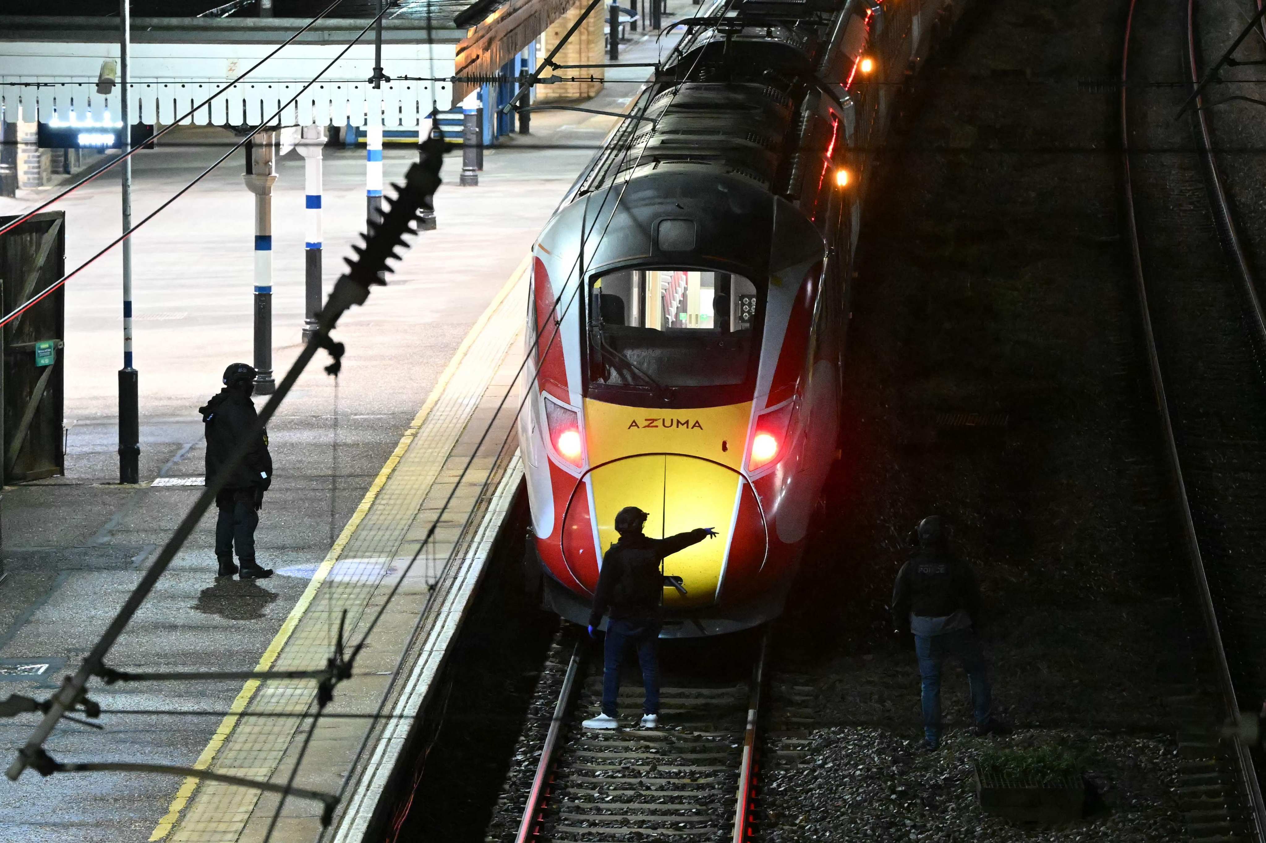 Police officers and search the track in front of a train in Huntingdon, England, on Saturday following a stabbing spree. Photo: AFP