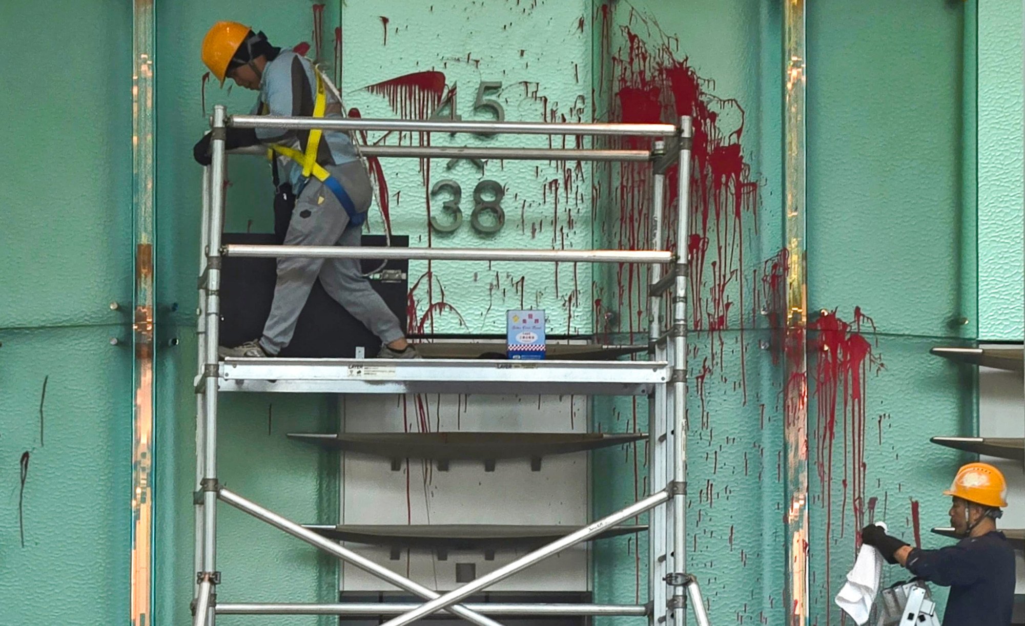Workers clean up the red paint splashed at the Cheung Kong Center. Photo: Handout
