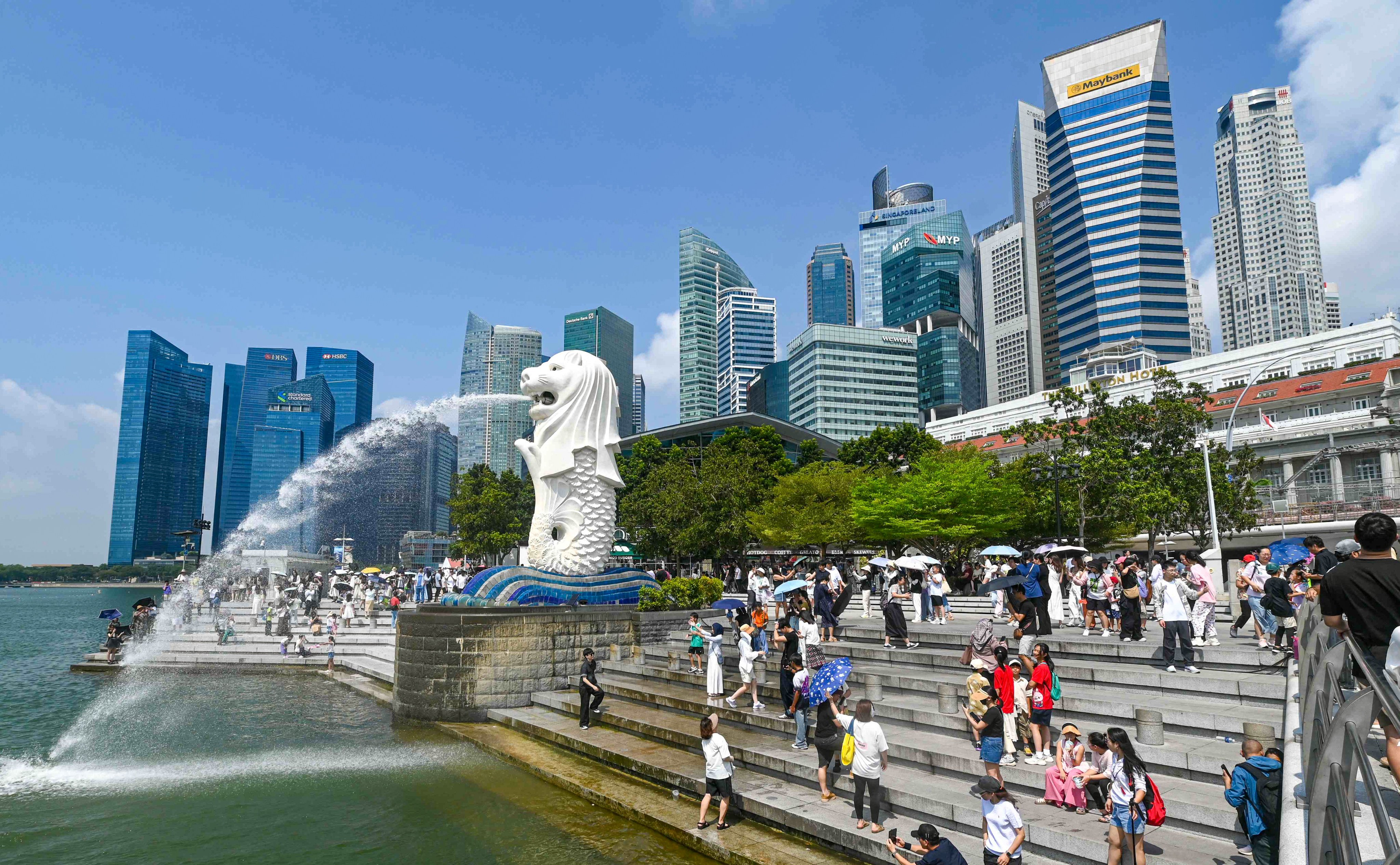 People take pictures next to the Merlion statue at the Marina Bay waterfront in Singapore. The city state has passed a law punishing scammers with six to 24 strokes of the cane. Photo: AFP