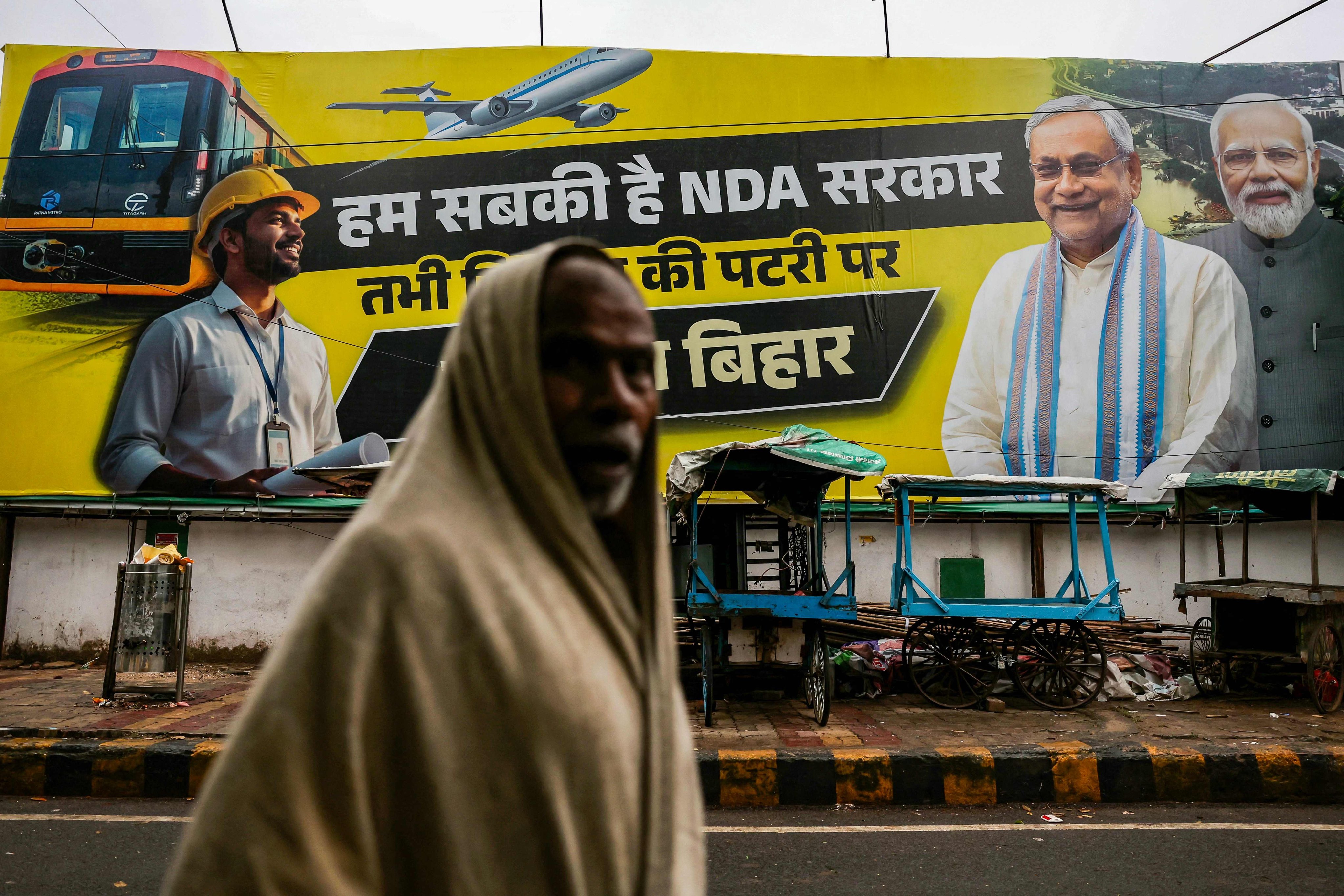 A man walks past a banner showing Indian Prime Minister Narendra Modi (right) and Bihar Chief Minister Nitish Kumar (second right) in Patna on Saturday ahead of the state assembly elections. Photo: AFP