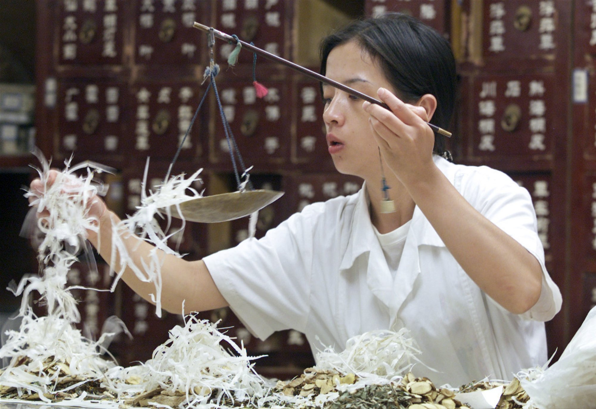 A Chinese pharmacist prepares a prescription of traditional herbal medicine at a store in Beijing. Photo: Reuters/Guang Niu