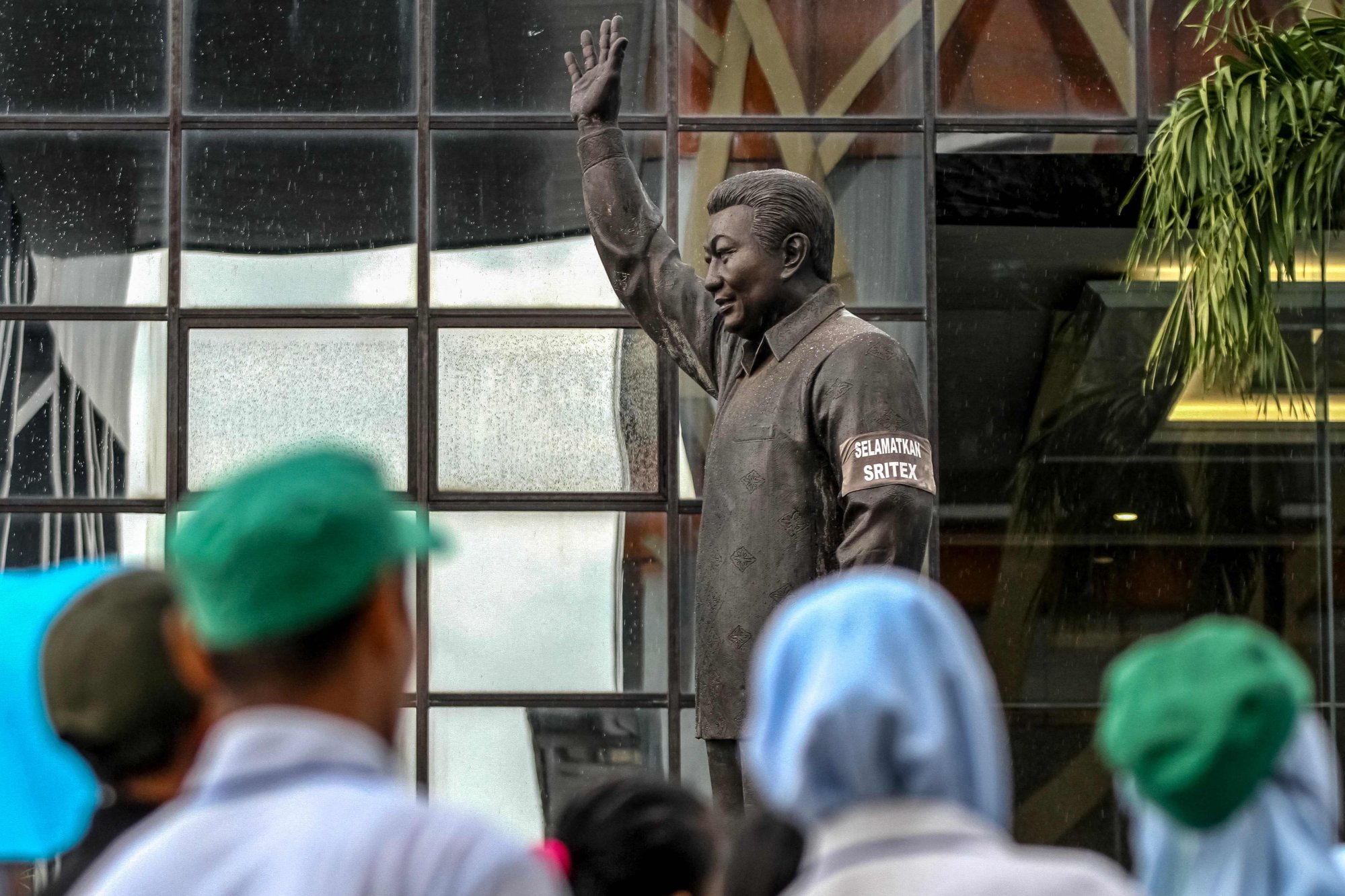 An armband with the words “Save Sritex” is seen on the arm of Sritex founder Lukminto’s statue while textile factory workers listen to a farewell speech during the mass lay-offs on February 28. Photo: AFP An armband with the words “Save Sritex” is seen on the arm of Sritex founder Lukminto’s statue while textile factory workers listen to a farewell speech during the mass lay-offs on February 28. Photo: AFP