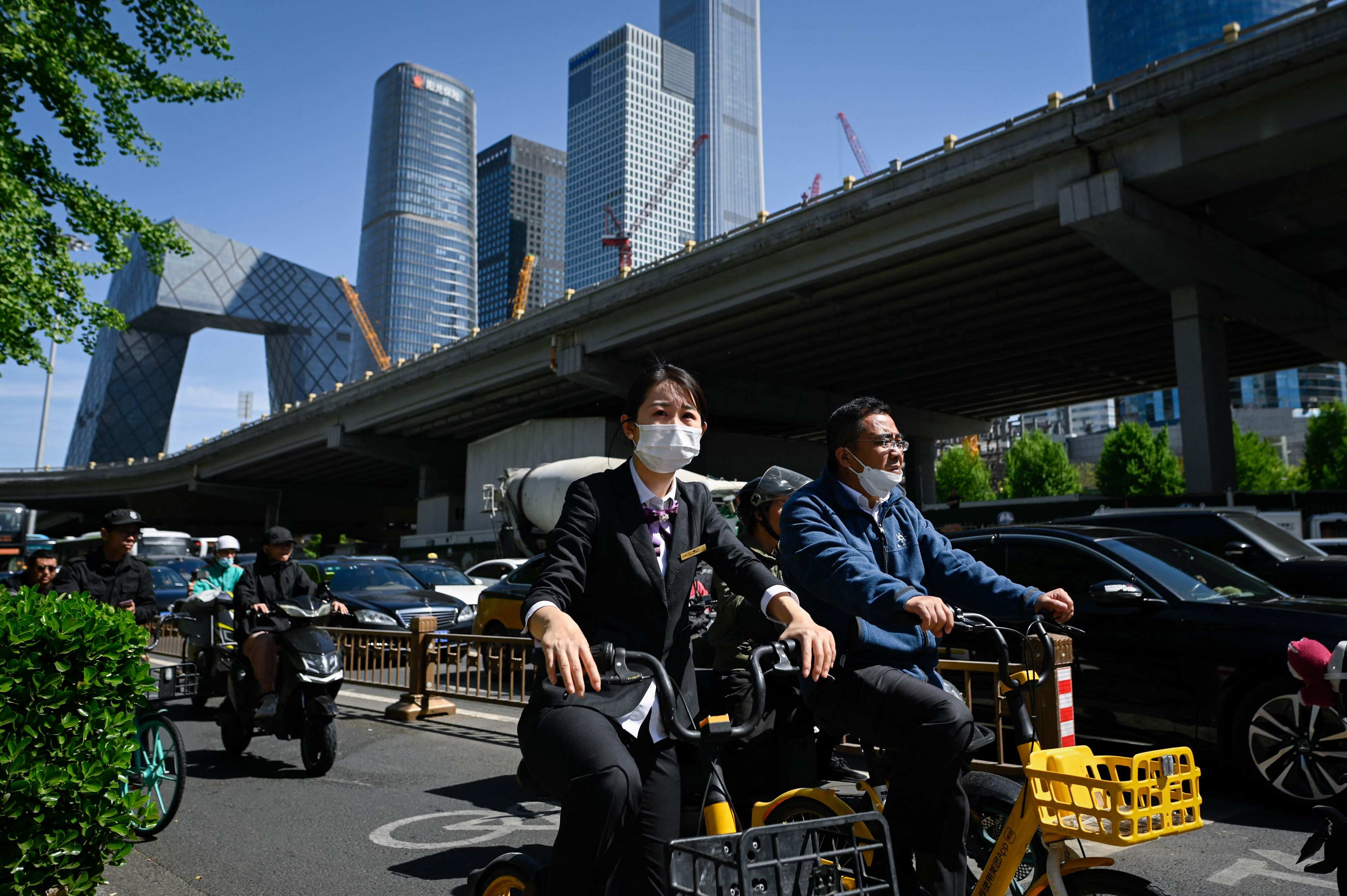 People ride bicycles along a street in Beijing’s business district on April 16, 2024. Photo: AFP