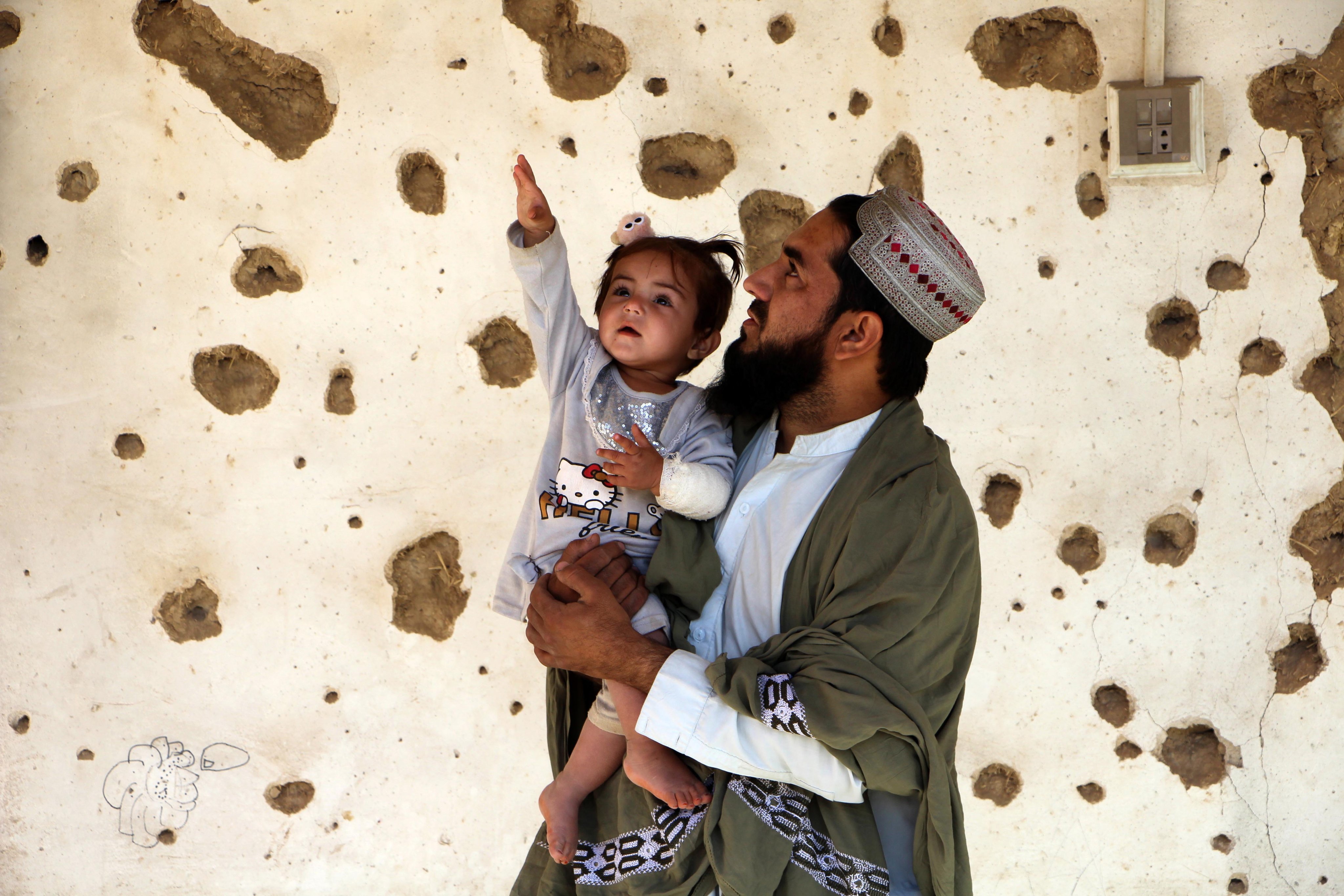 A man and child stand by a house allegedly damaged by cross-border fire from Pakistan in Spin Boldak, Afghanistan, on Friday. Photo: EPA