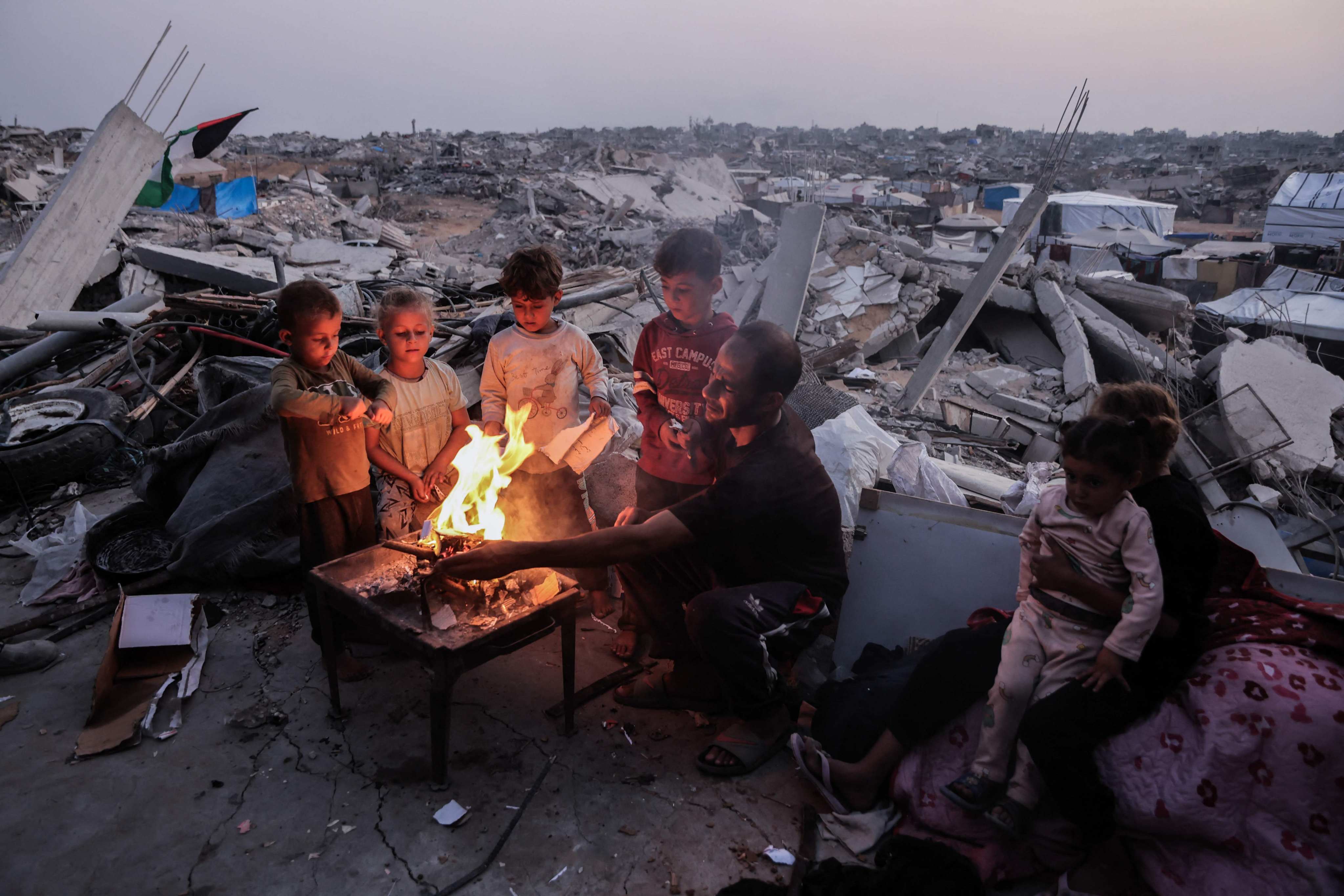 A Palestinian family sits around a fire amid the rubble of destroyed buildings in Jabalia, in the northern Gaza Strip, on Friday. Photo: AFP