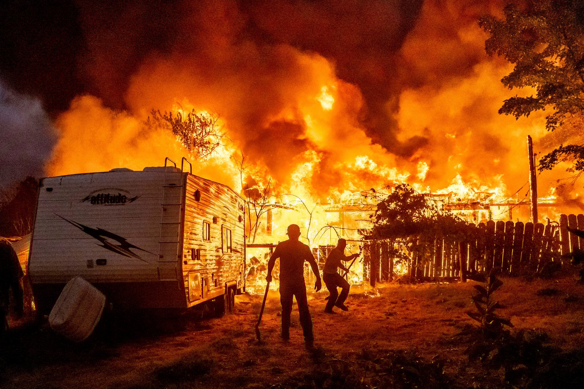 Residents work to stop flames from a burning home spreading in Tuolumne County, California, during a wildfire in September. Photo: AP Residents work to stop flames from a burning home spreading in Tuolumne County, California, during a wildfire in September. Photo: AP