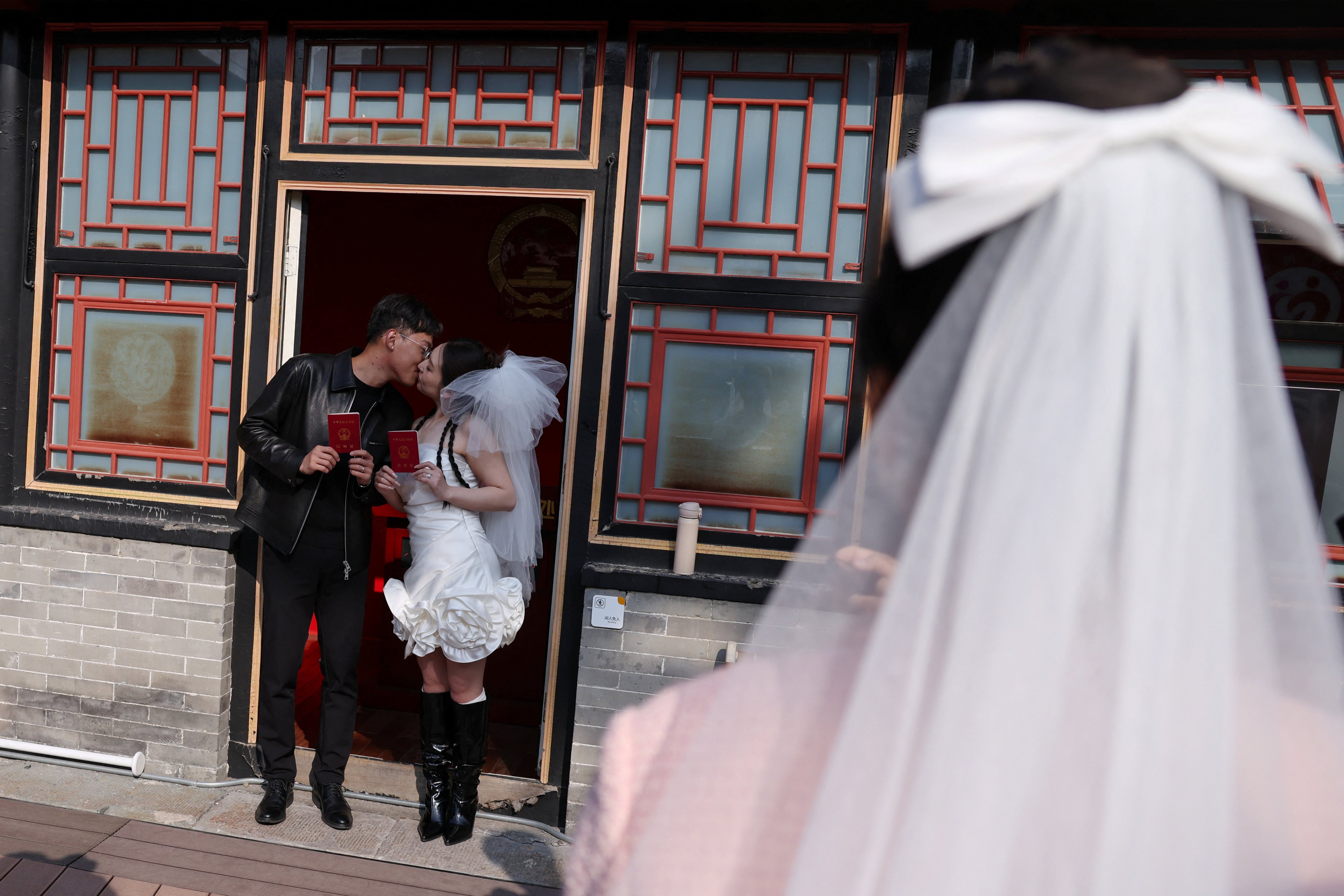 A newlywed couple pose with their marriage certificates after they register at the Huguo Guanyin Temple, in Beijing, China, on October 28, 2025. Photo: Reuters