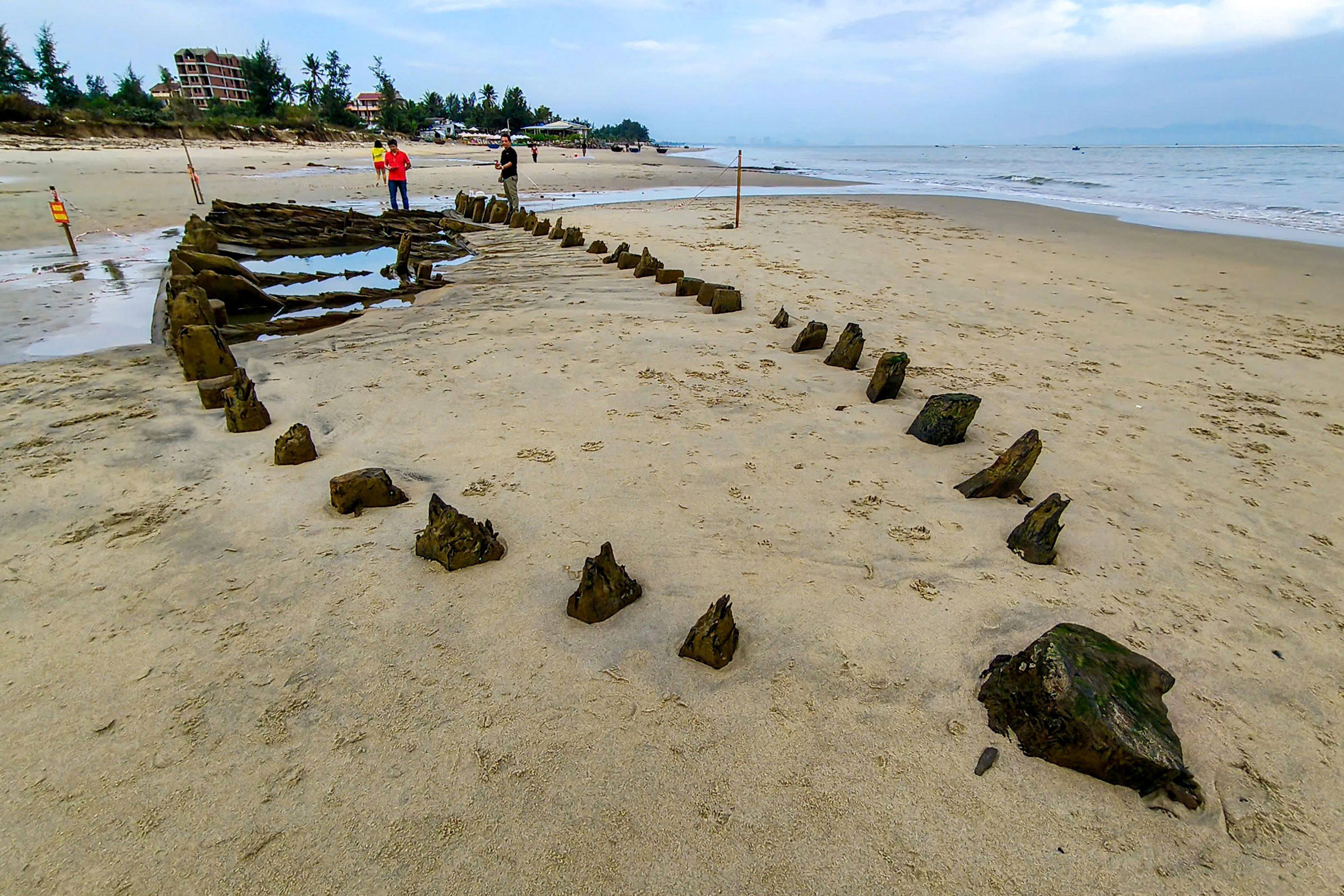 People look at a centuries-old shipwreck uncovered in the aftermath of Typhoon Kalmaegi on a beach off Hoi An, Vietnam, on Monday. Photo: AFP