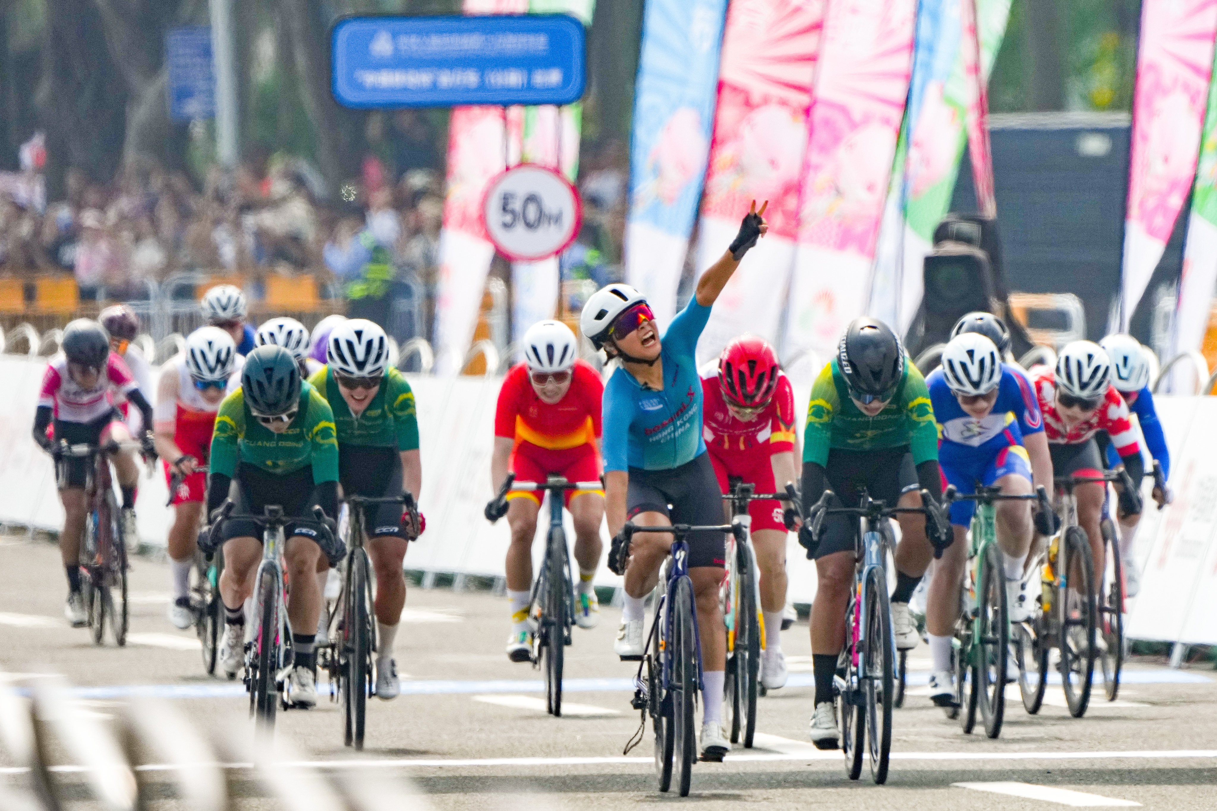 Ceci Lee (centre) raises her arm in victory after her road race gold medal win in Zhuhai. Photo: Eugene Lee