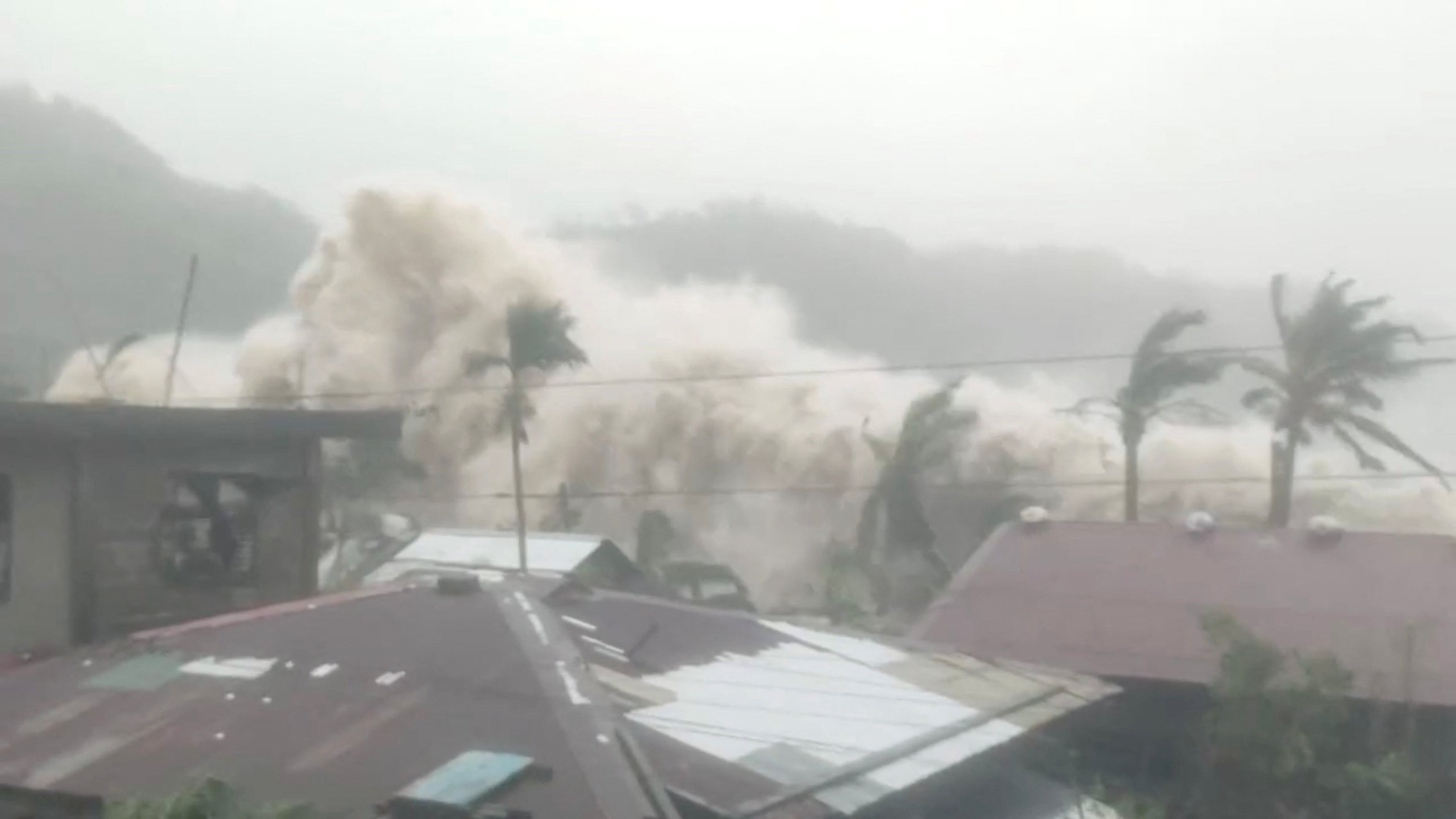 Palm trees and residential rooftops stand as strong waves caused by Super Typhoon Fung-wong crash, in Sicmil, Gigmoto, Catanduanes, Philippines, November 9, 2025, in this screengrab obtained from a social media video. Dyves Meno Turado/via REUTERS  THIS IMAGE HAS BEEN SUPPLIED BY A THIRD PARTY. MANDATORY CREDIT. NO RESALES. NO ARCHIVES. VERIFICATION: Reuters was able to independently verify the location with the palm trees, the position and outline of the buildings that matched by the file and satellite imagery of the area. The date was verified by corroborating weather and local Media reports.