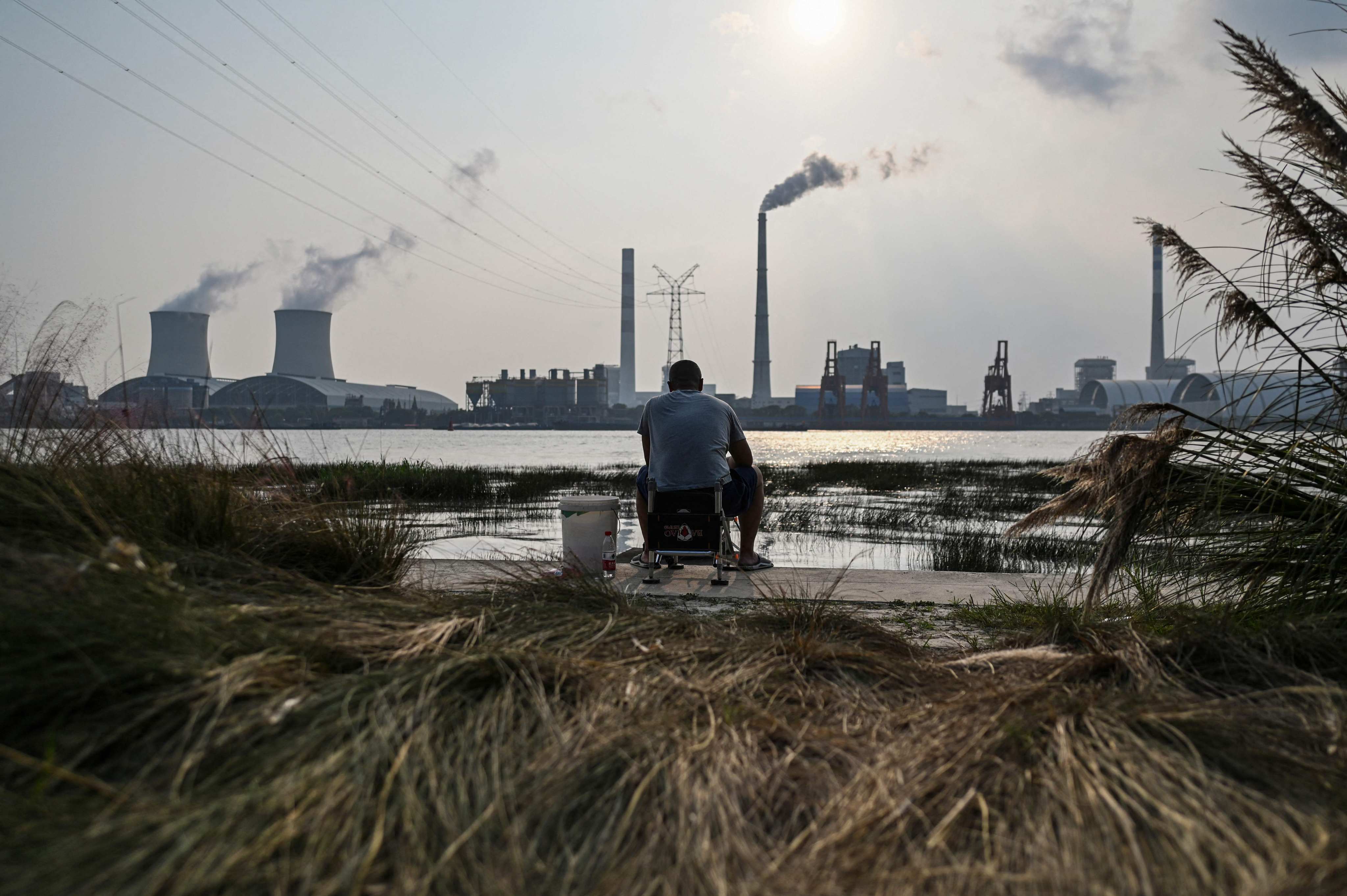 An angler fishes across from the Wujing Power Station in Shanghai. China won’t back Brazil’s key rainforest initiative for the time being. Photo: AFP
