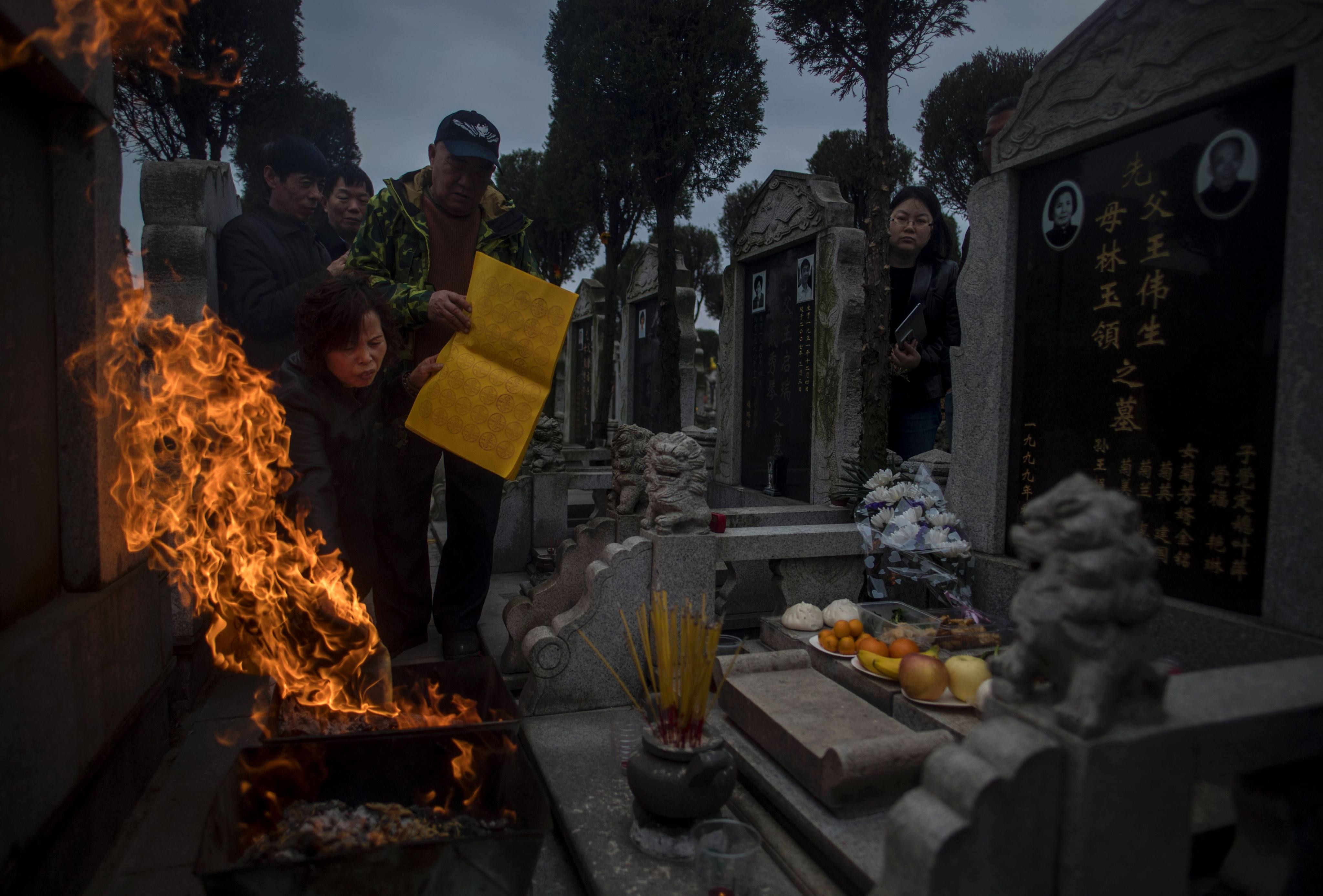Ghost money and incense sticks are burnt in front of a gravestone during the Ching Ming Festival at a cemetery in Shanghai in 2017. Photo: AFP
