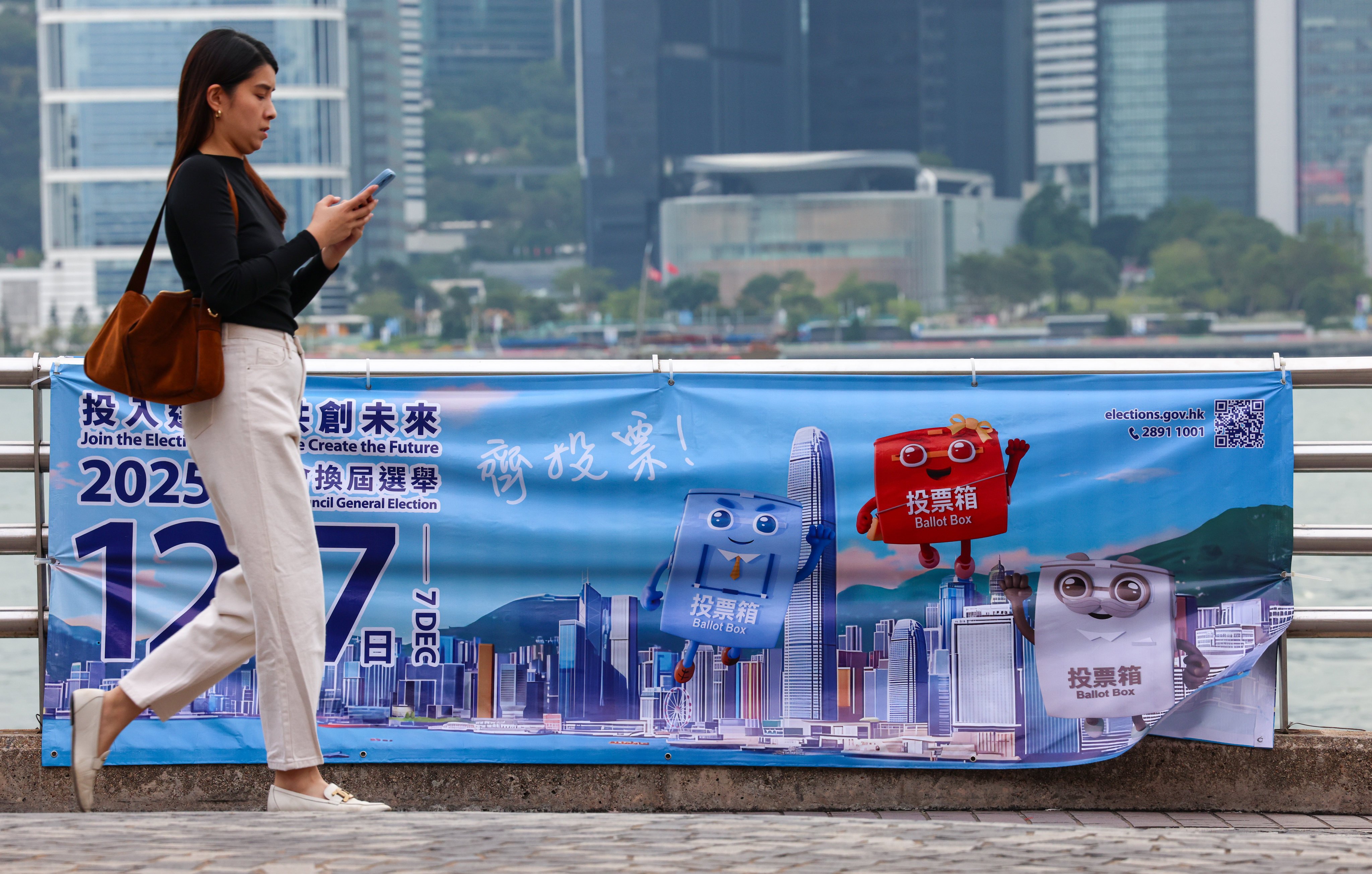 A woman walks past a poster for Hong Kong’s 2025 Legislative Council election, at the Tsim Sha Tsui Pier, on November 6. Photo: Jelly Tse