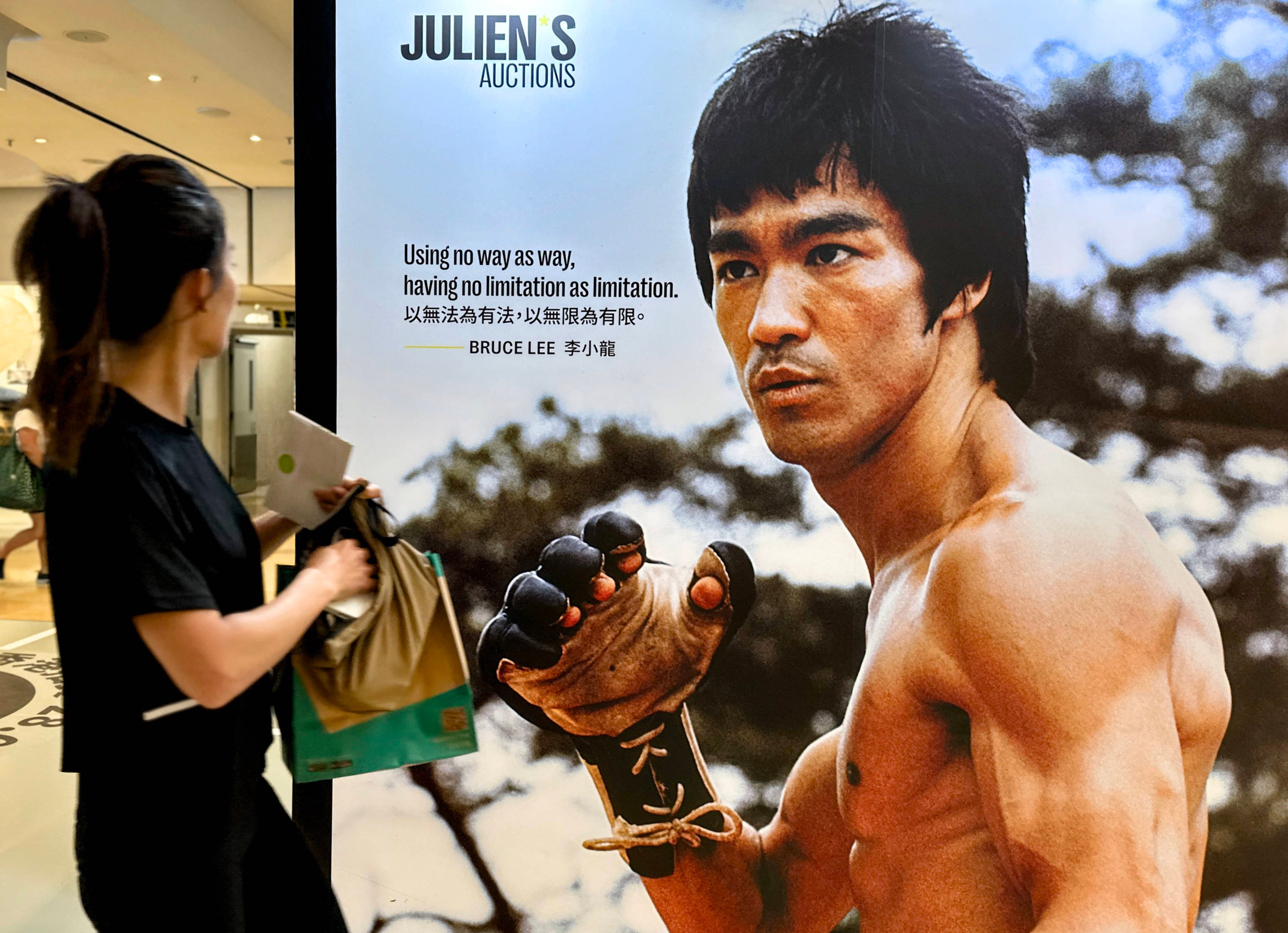 A woman looks at a Bruce Lee poster in Hong Kong in 2024. Half a century after his death, Lee is still an icon from Asia to the United States. Jeff Chang considers why in his biography of the kung fu movie star. Photo: Zuma Press/TNS