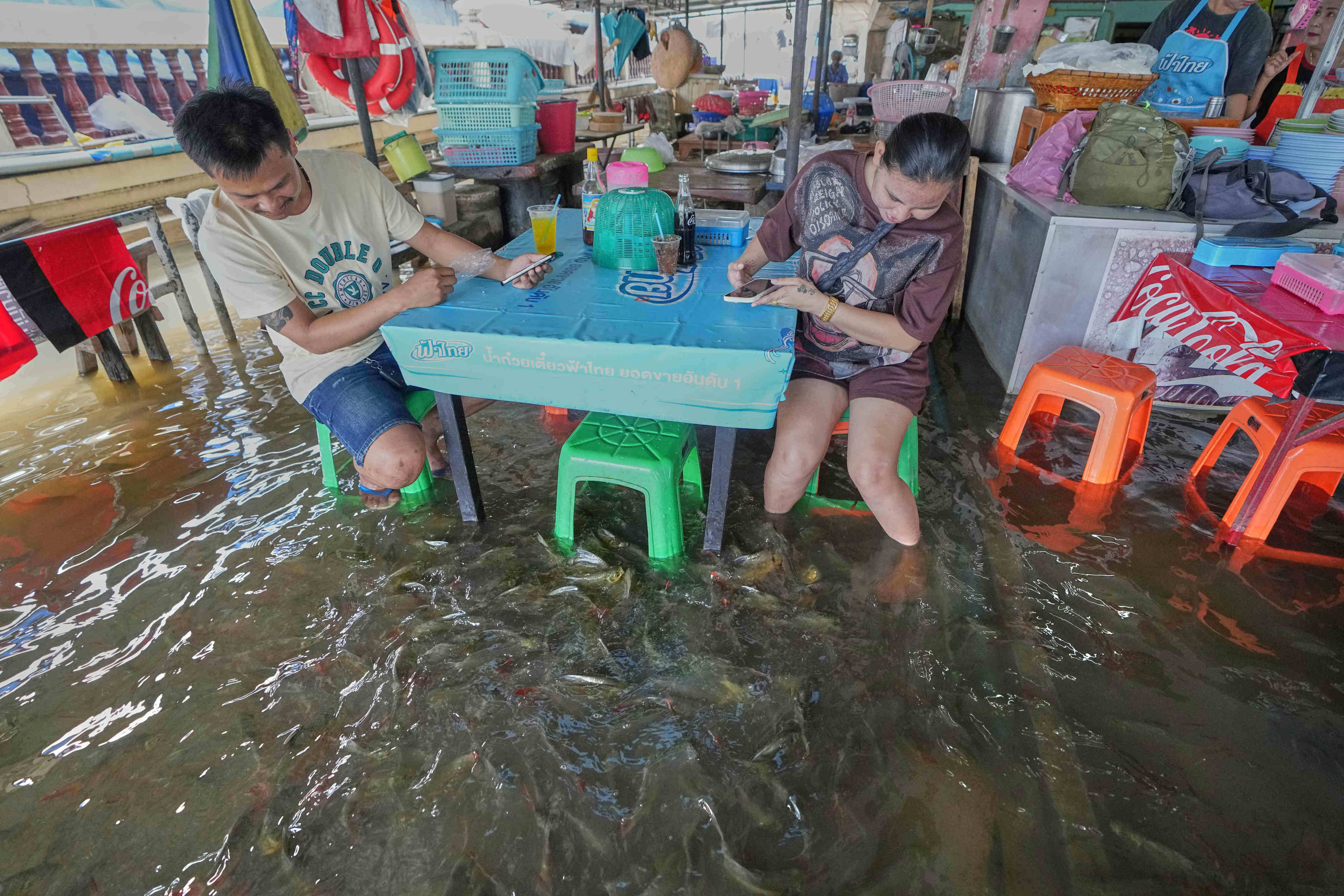 Diners at the Pa Jit restaurant watch fish swim in the aisles due to flooding from the Tha Chin River in Thailand’s Nakhon Pathom Province on Friday. Photo: AP