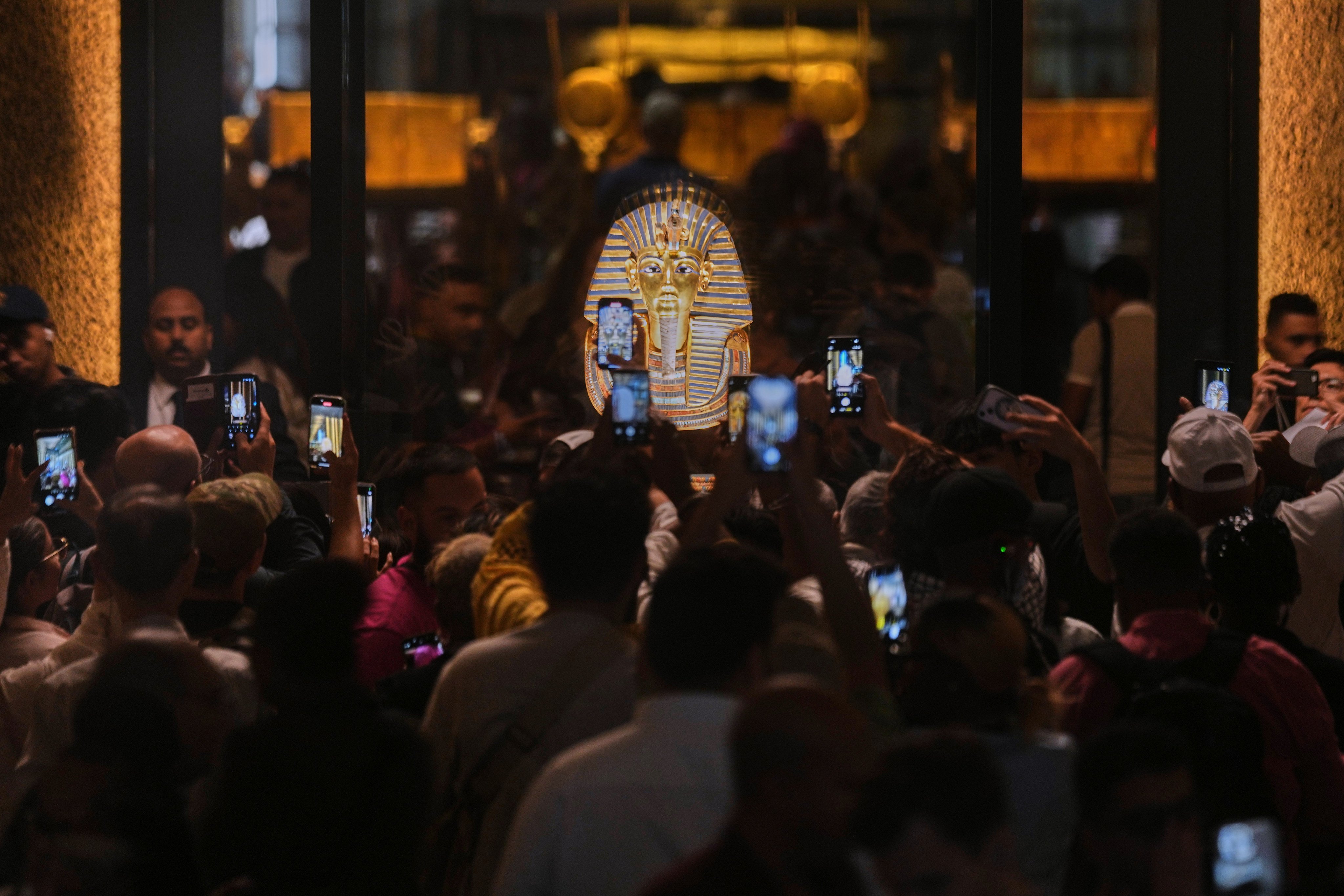 People hold mobile devices in front of the golden burial mask of King Tutankhamun. Photo: AP