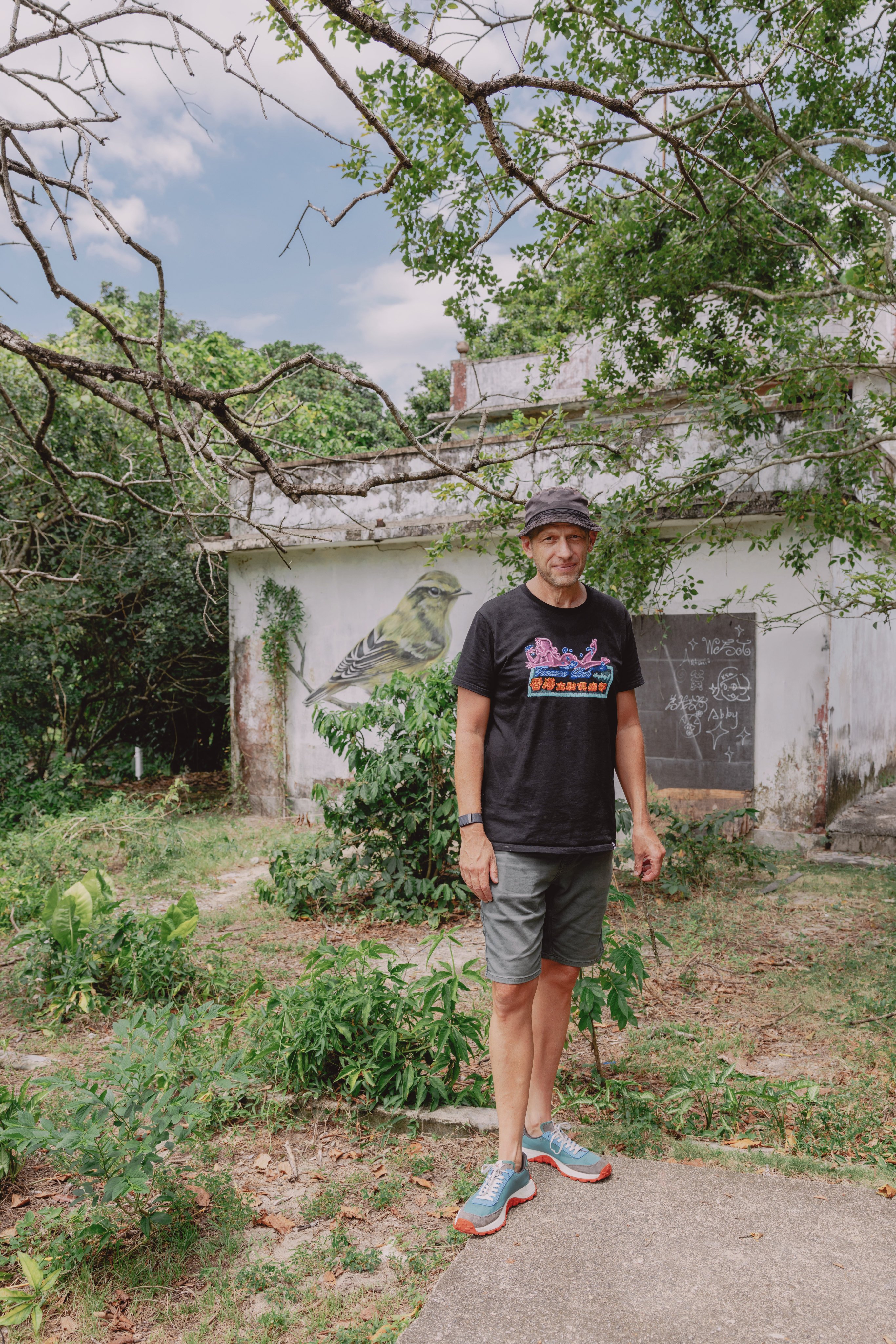 Dominic Johnson-Hill in front of a mural featuring a yellow-browed warbler in Mui Wo, Lantau Island. Photo: Jocelyn Tam