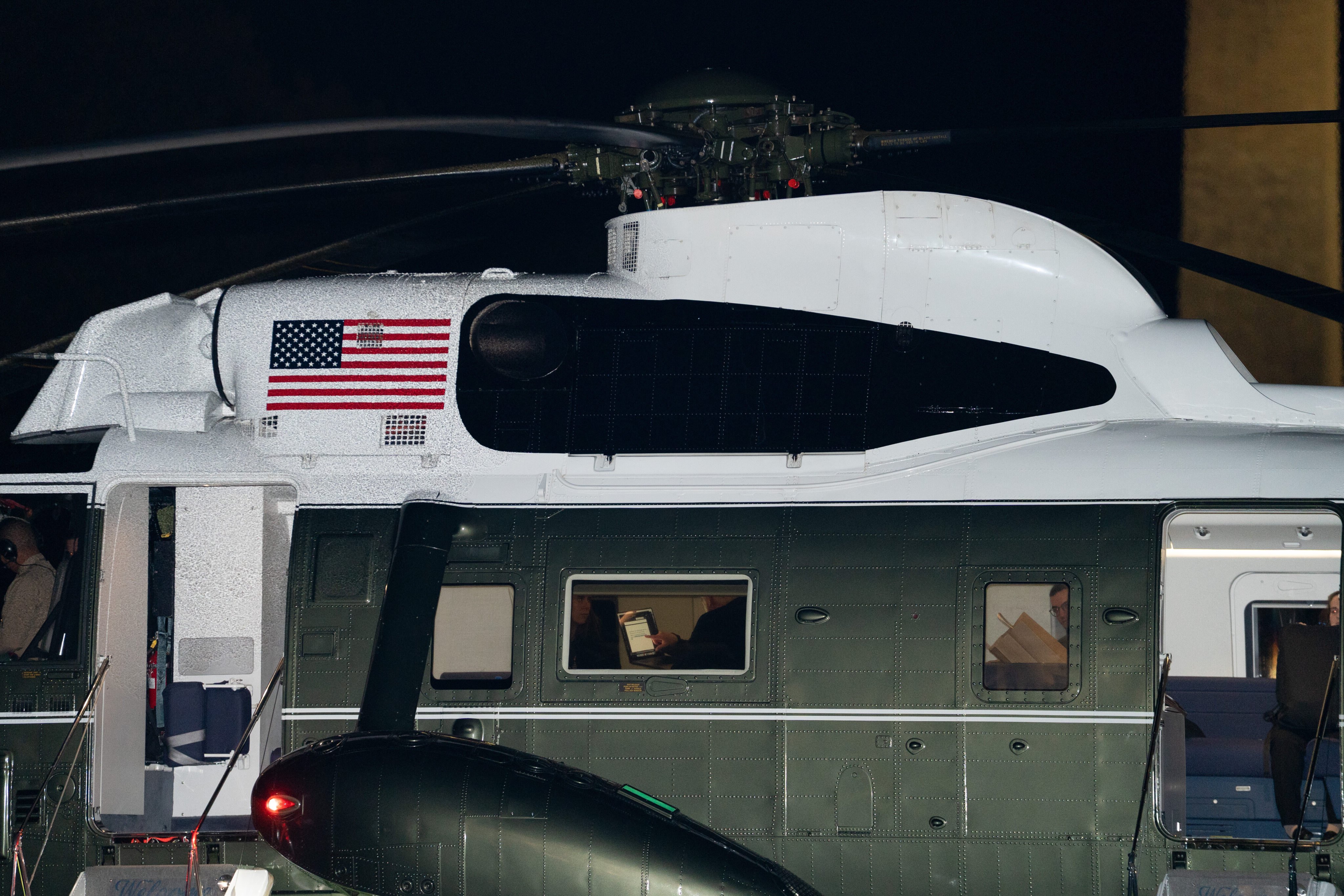 US President Donald Trump reads text from a laptop aboard Marine One on Sunday. Photo: AP