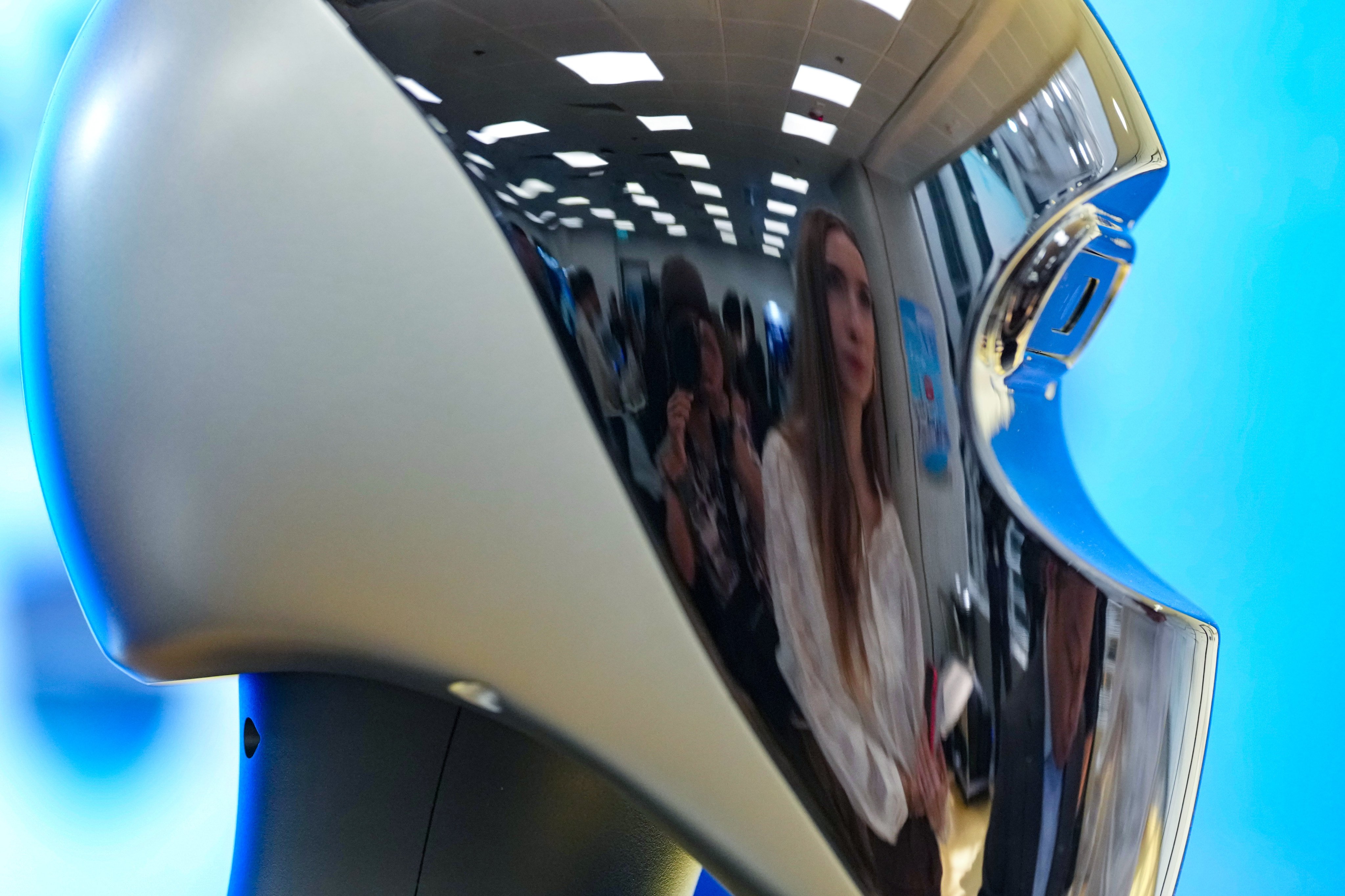 Visitors to the AI and Robotics Fest at the Hong Kong Productivity Council building in Kowloon Tong are reflected on the head of a humanoid robot, on November 10. Photo: Karma Lo