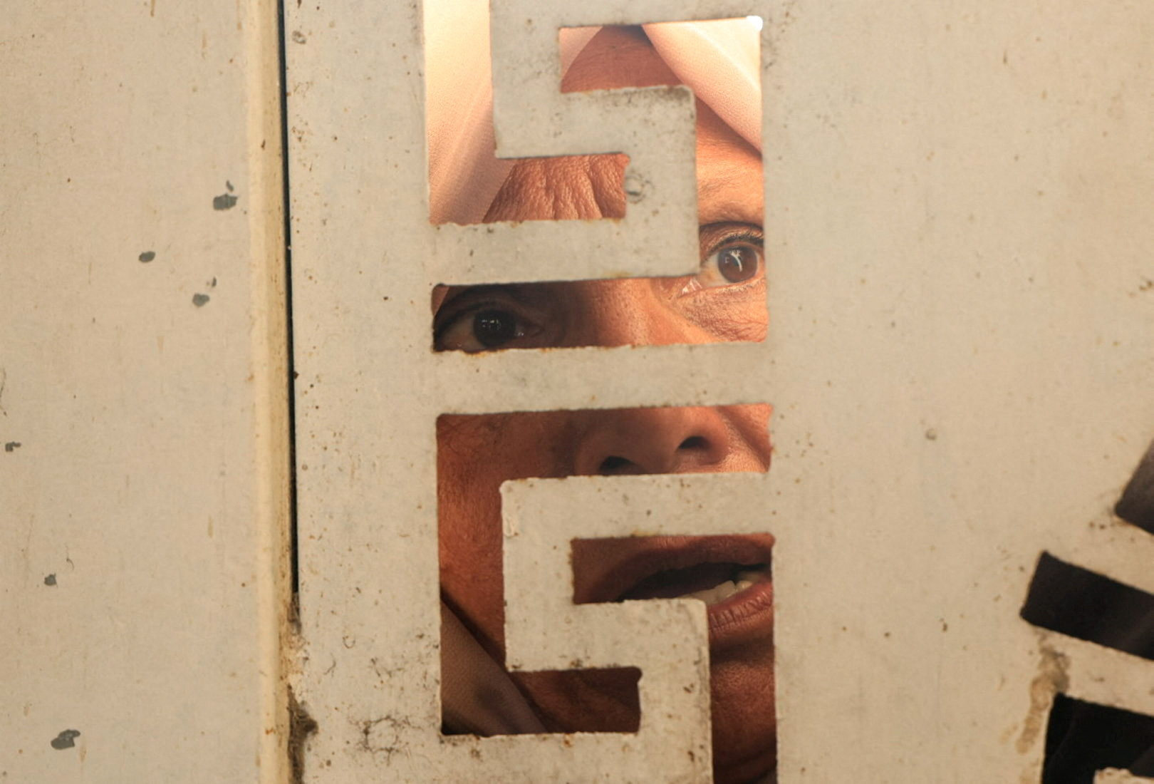 A woman looks through a gate as Palestinians wait to buy bread from a distribution point in Khan Younis in the southern Gaza Strip on November 17. Photo: Reuters