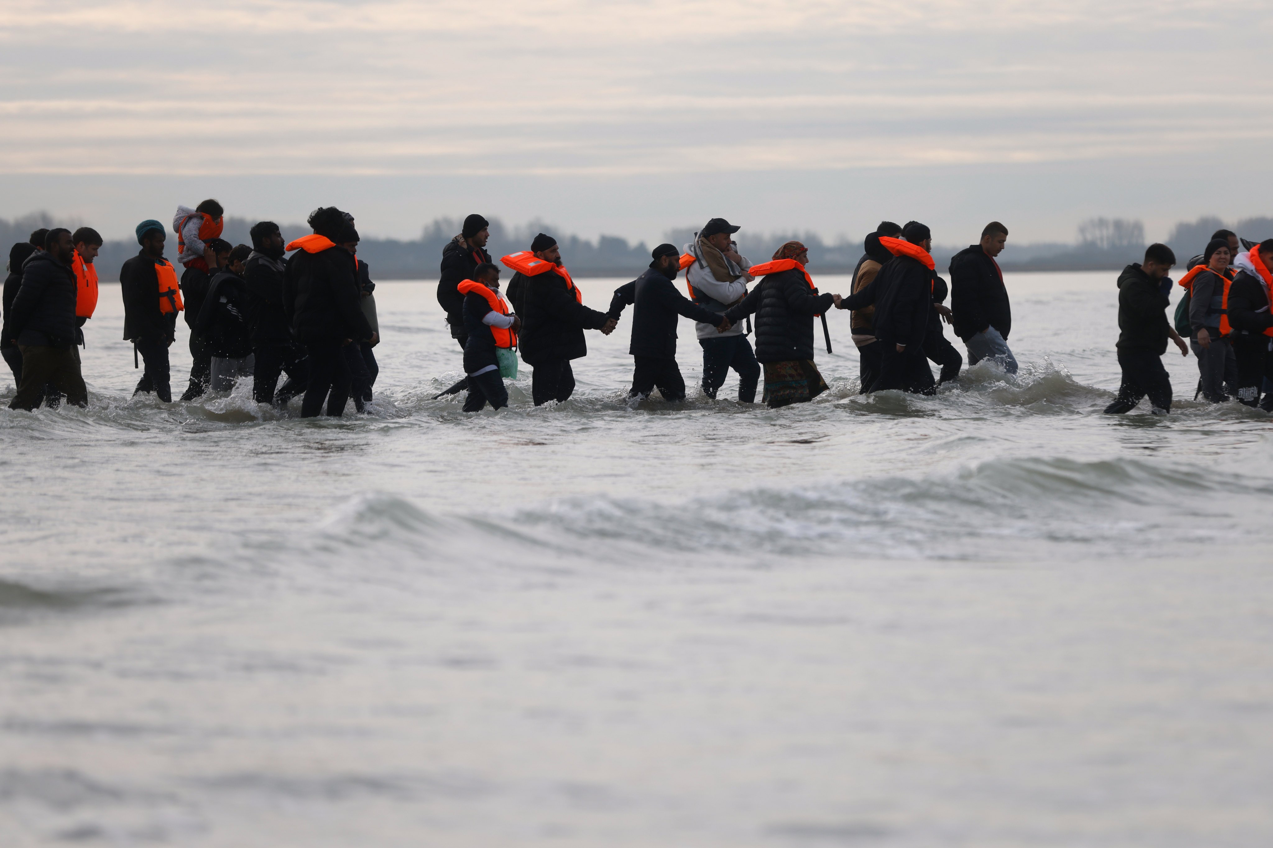 Migrants in Gravelines, northern France, walk in the water to board a small boat in an attempt to reach Britain. Photo: AP