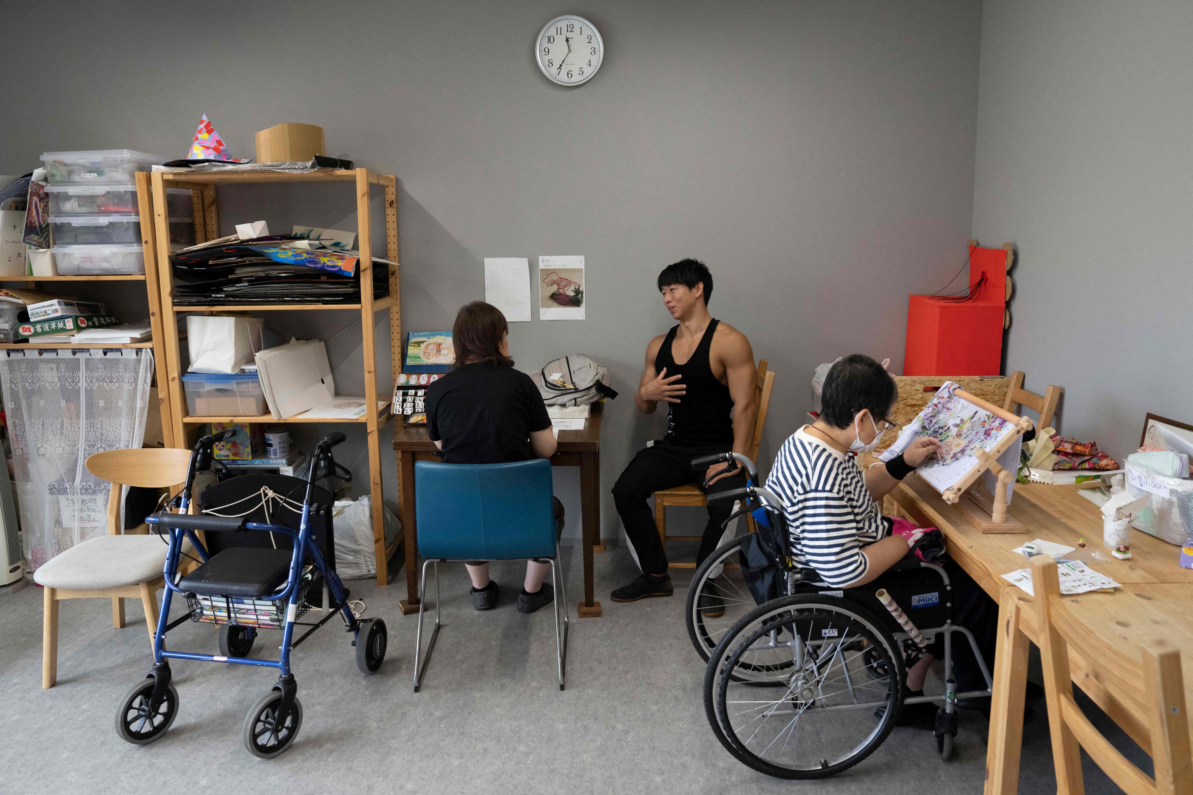 Care worker and bodybuilder Takuya Usui (centre) chats with a resident at a care home for people with disabilities operated by Visionary in Ichinomiya, Aichi prefecture. Photo: AFP