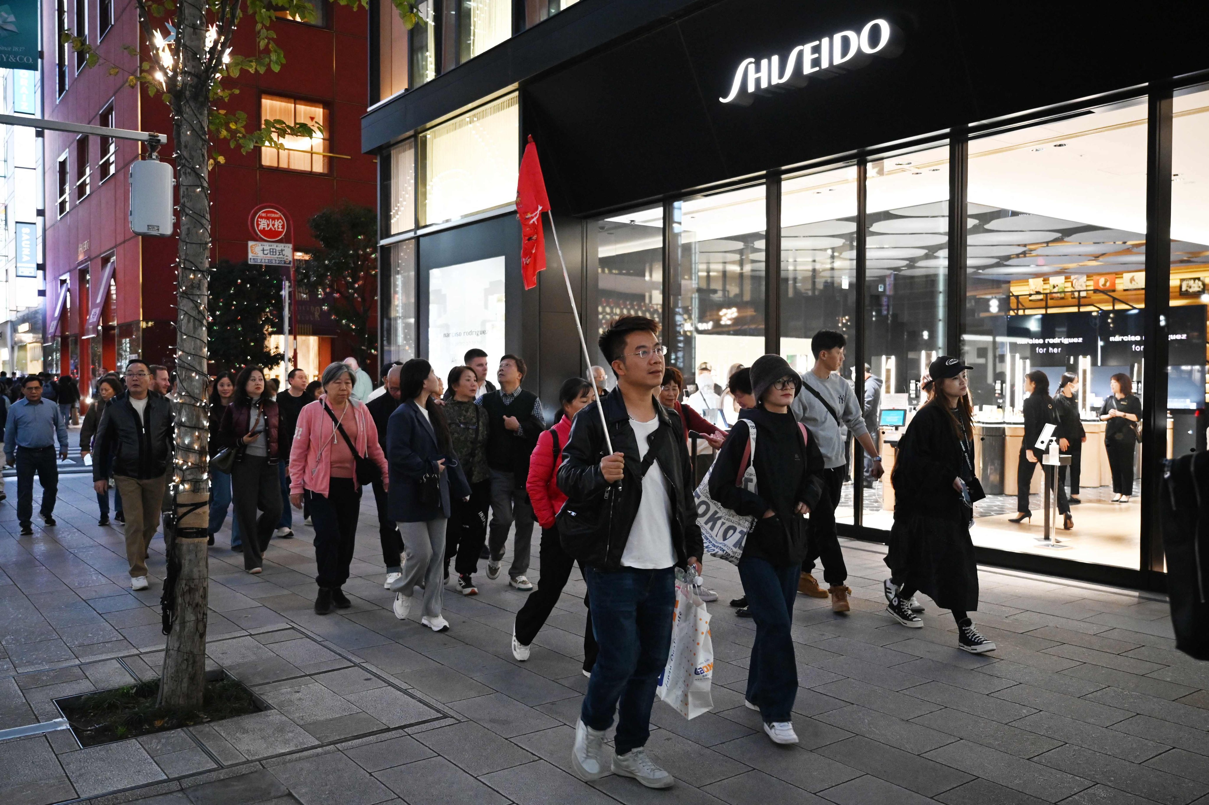 A Chinese tour group walks past a Shiseido store in Tokyo on November 17, 2025. Photo: AFP