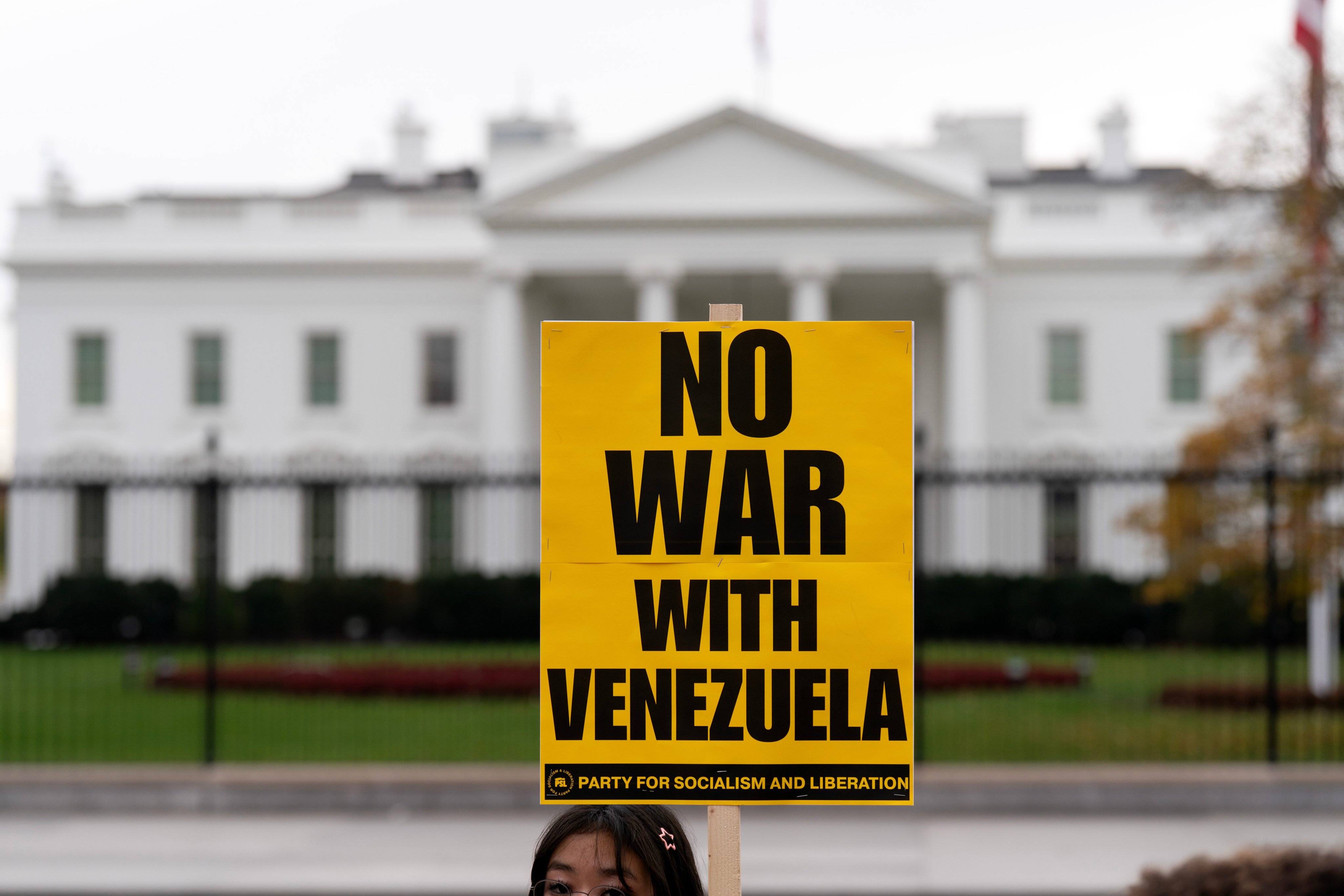 A demonstrator holds a “No War With Venezuela” sign while protesting outside the White House in Washington, on November 15. Photo: AP