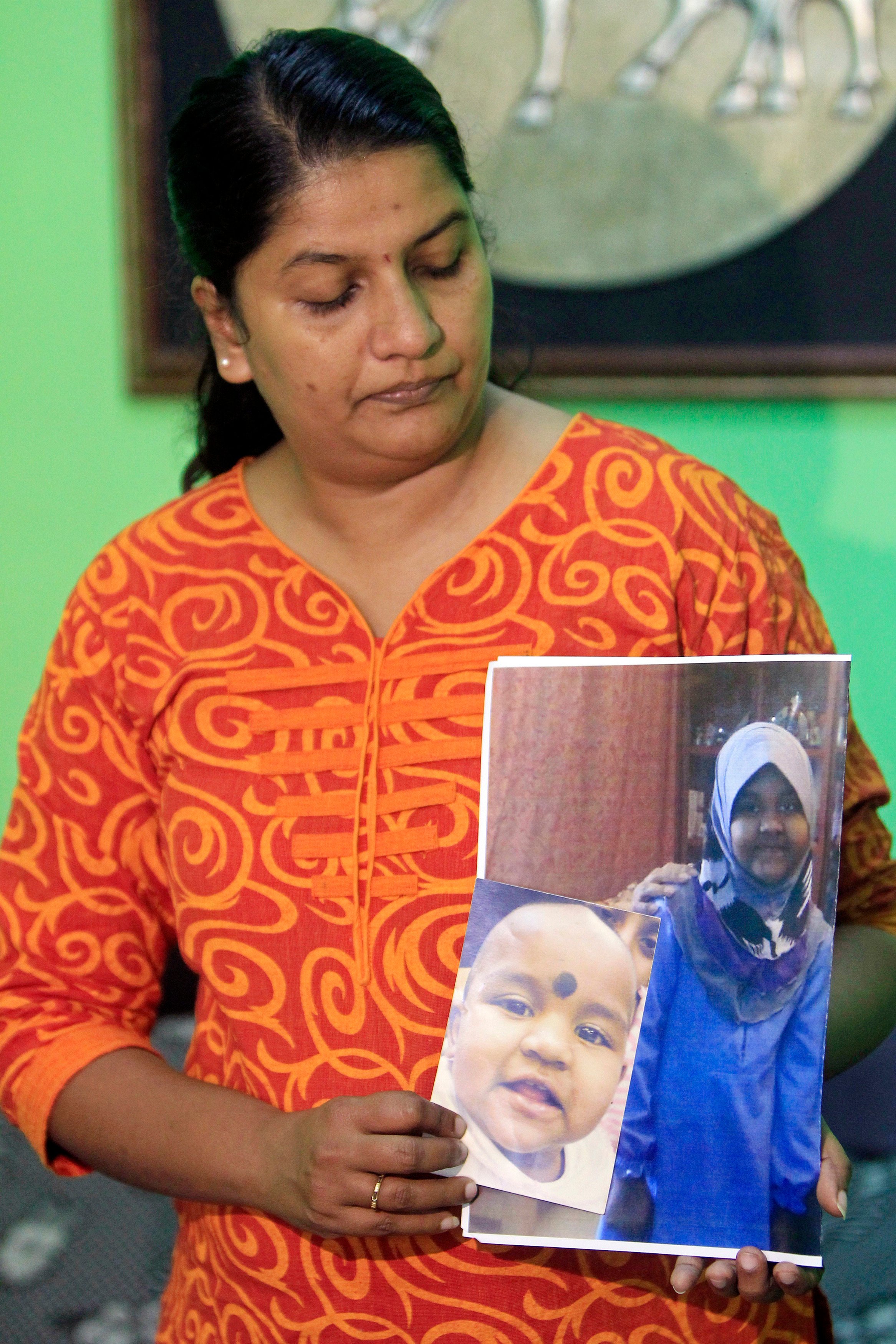 In this 2014 photo, M. Indira Gandhi shows photos of her youngest daughter Prasana Diksa at her house in Ipoh, Perak, Malaysia. Photo: AP
