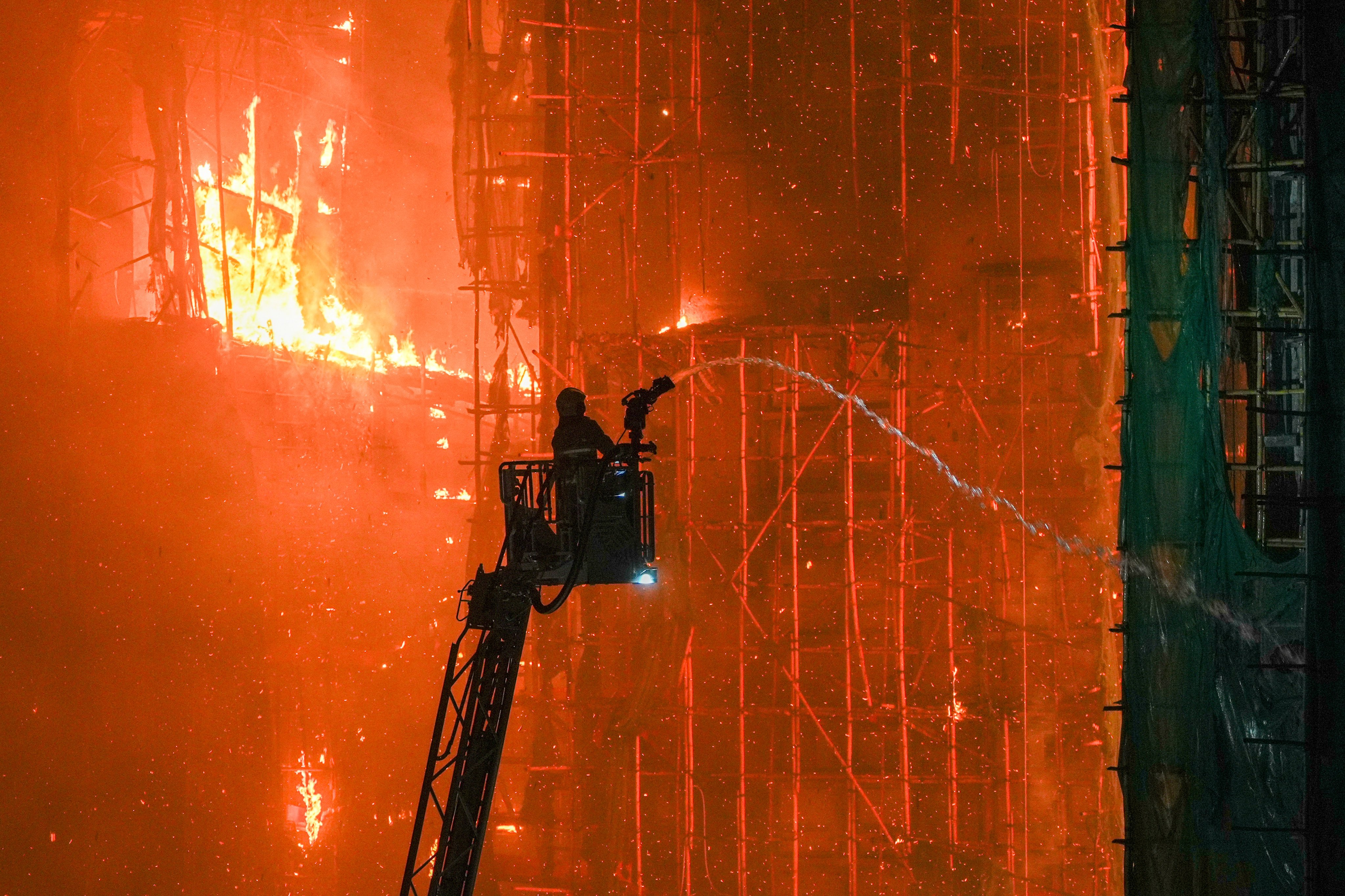 A firefighter shoots water at a  fire at Wang Fuk Court in Tai Po, Hong Kong, on November 26, 2025. All eight buildings on the estate had been covered in bamboo scaffolding amid ongoing renovation works. Photo: Eugene Lee