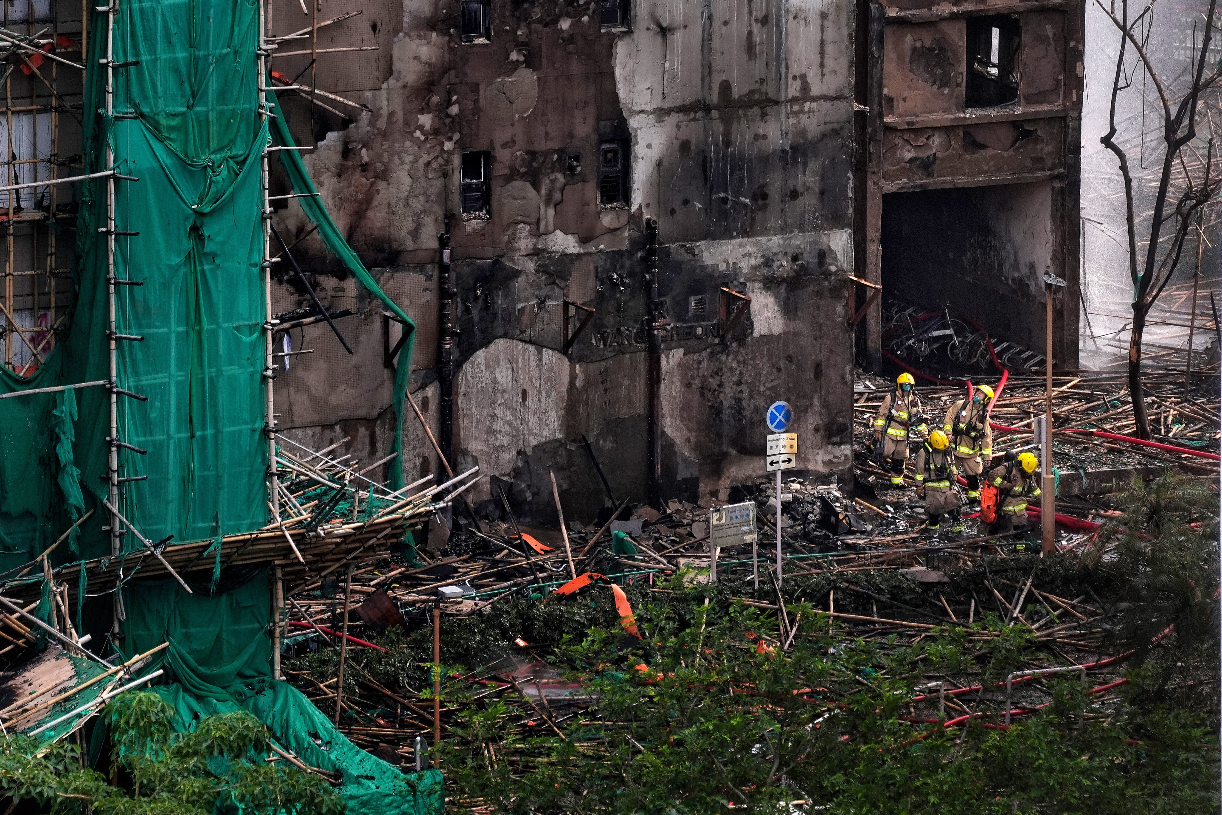 Firefighters emerge from a building in Wang Fuk Court. Questions have been raised about the green netting used on the bamboo scaffolding Photo: Elson Li