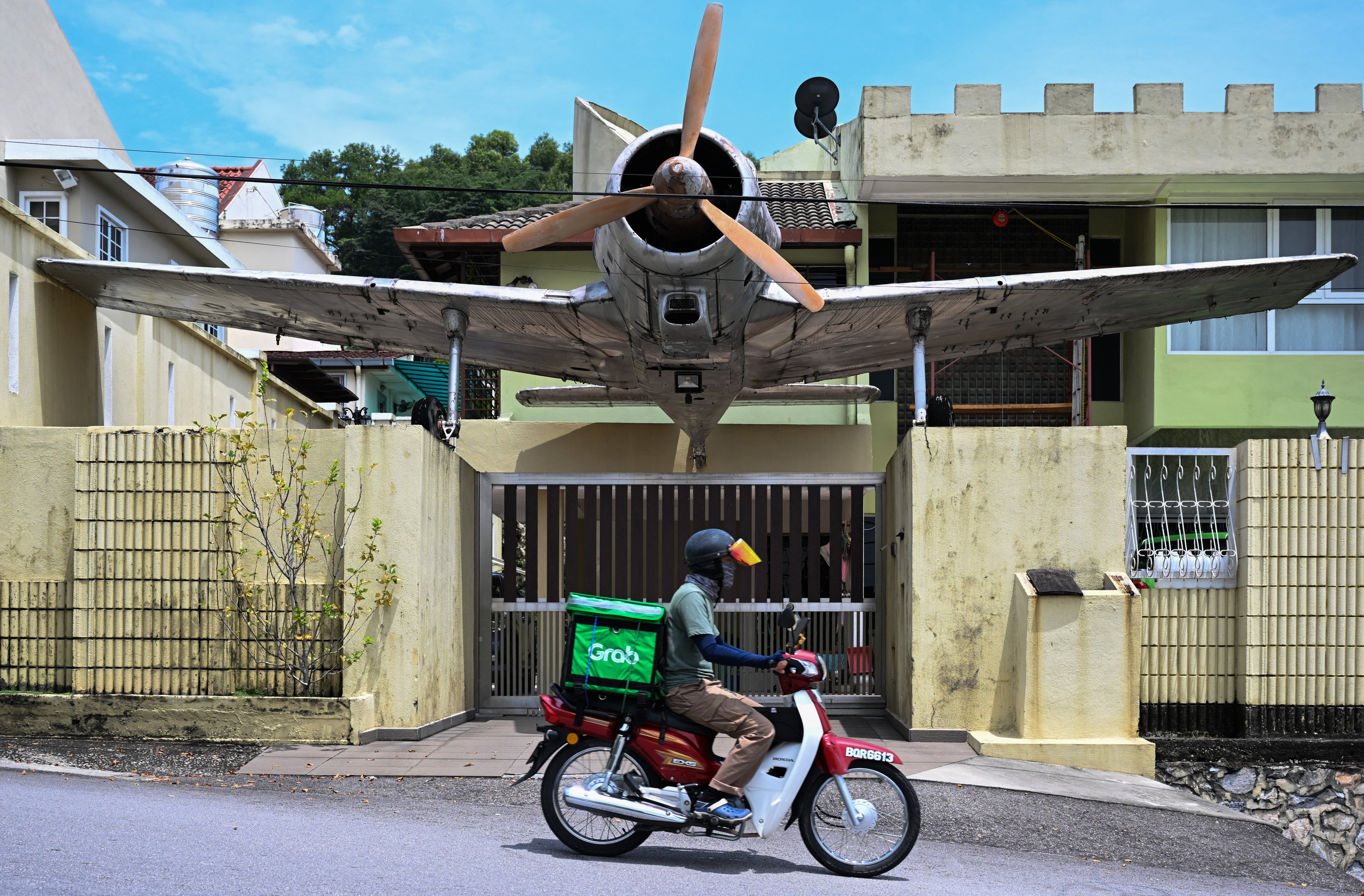A delivery rider for Grab passes in front of a house in Kuala Lumpur, Malaysia. Photo: AFP
