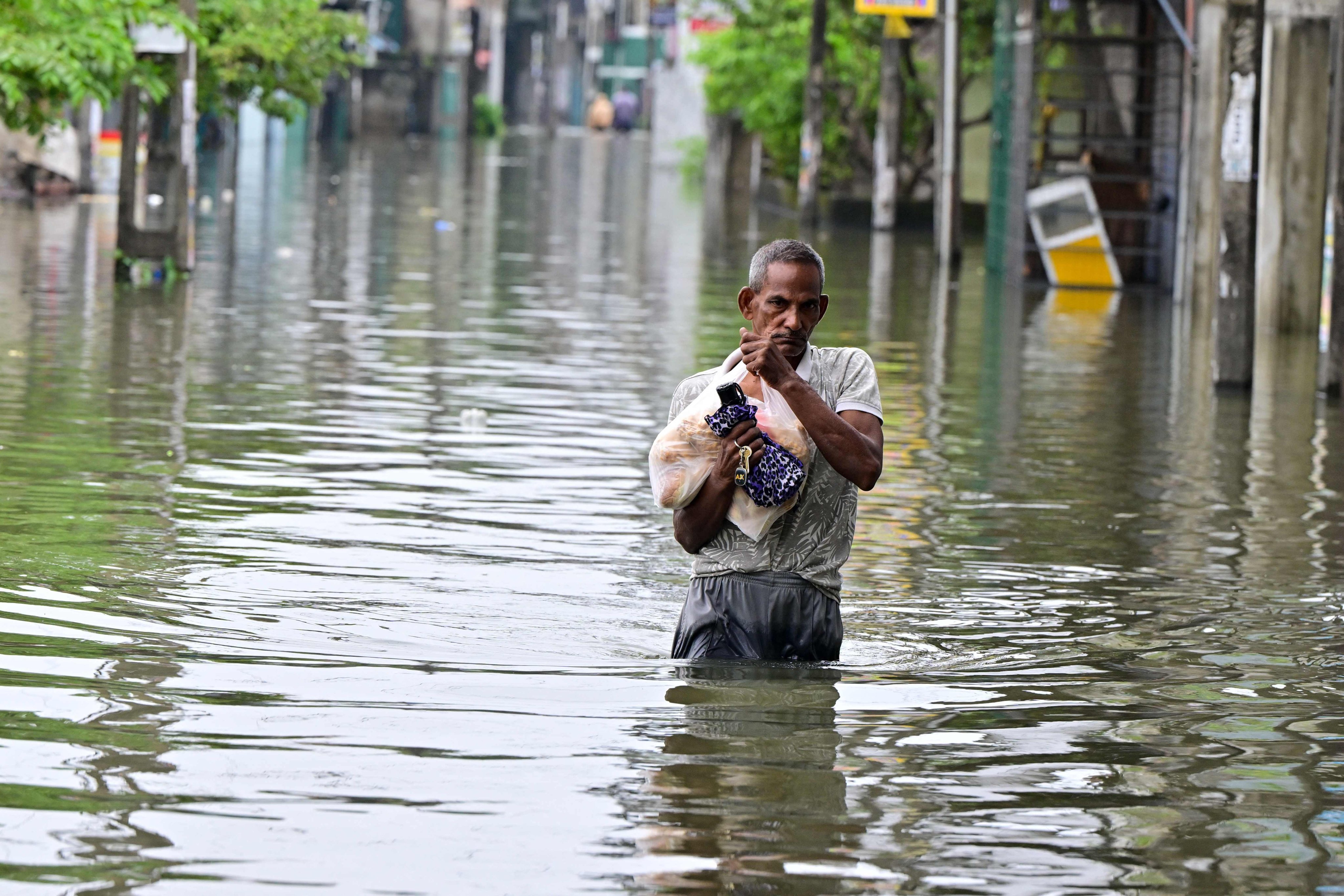 A man wades through a flooded road after heavy rainfall on the outskirts of Colombo on Saturday. Photo: AFP