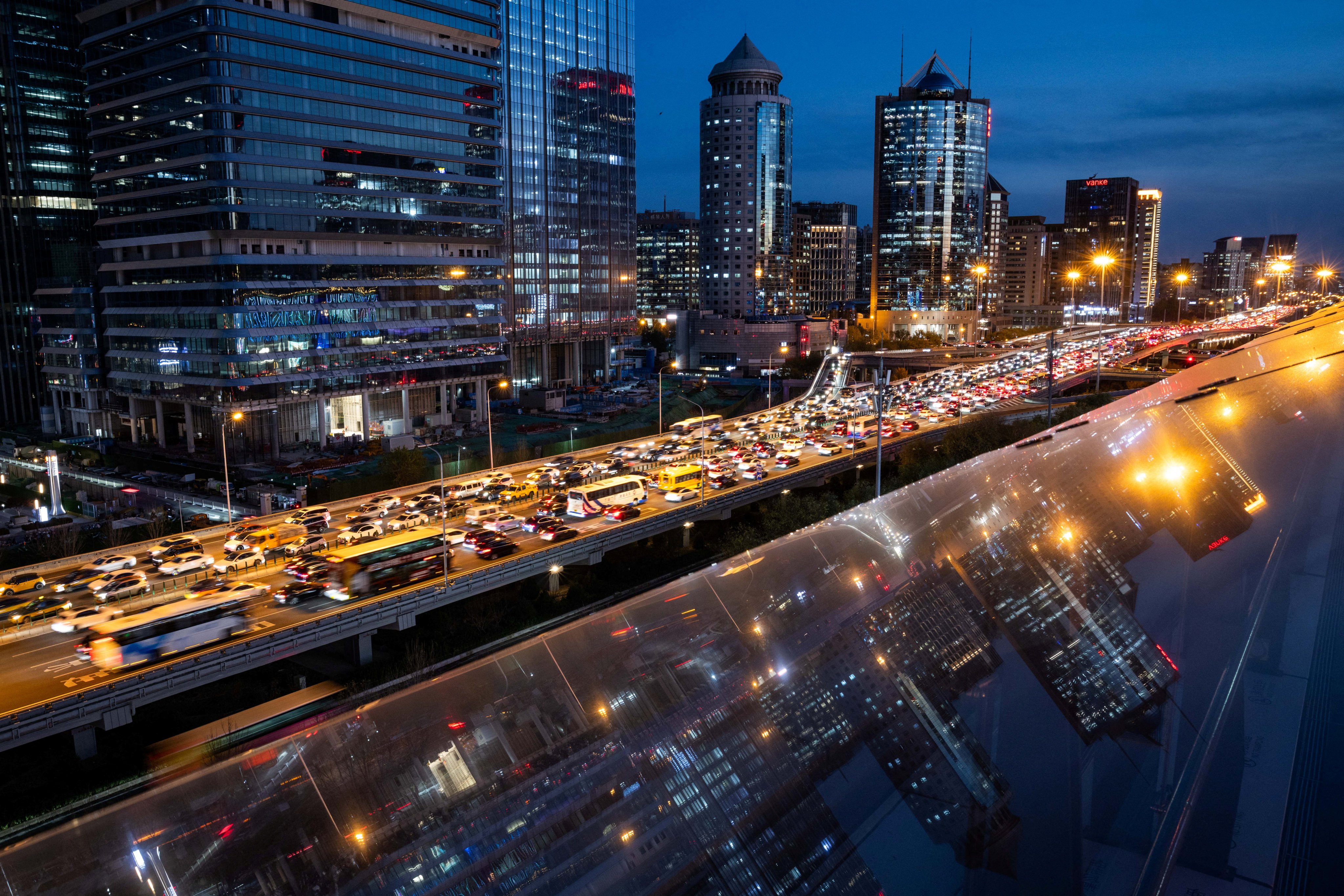 Traffic crawls on an elevated highway as buildings are reflected on a glass surface in Beijing’s central business district on November 12, 2025. Photo: Reuters