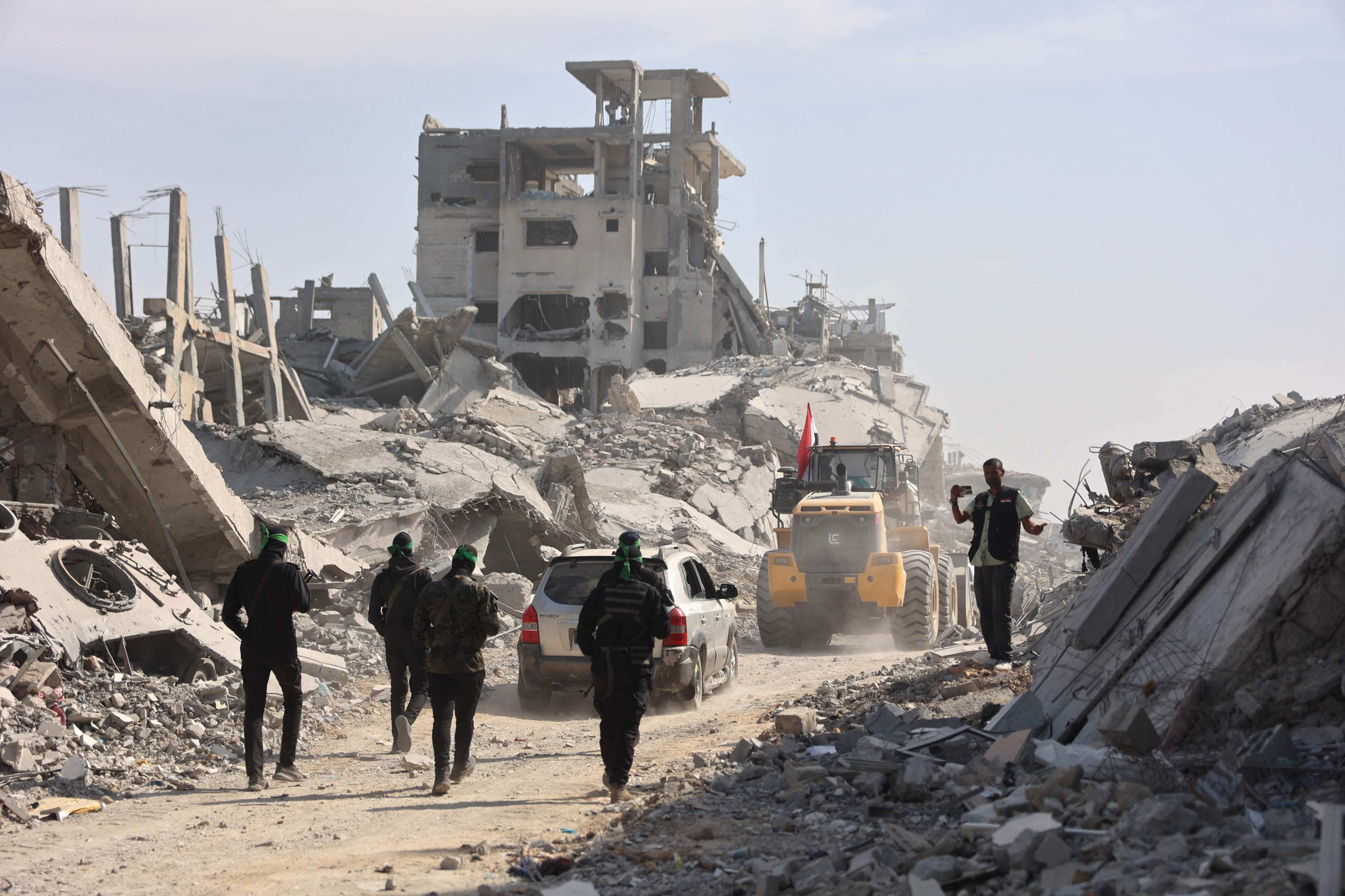 Armed Palestinian Hamas militants follow a digger which has been supplied by Egypt to search for bodies of killed Israeli hostages in Gaza City on November 2. Photo: AFP