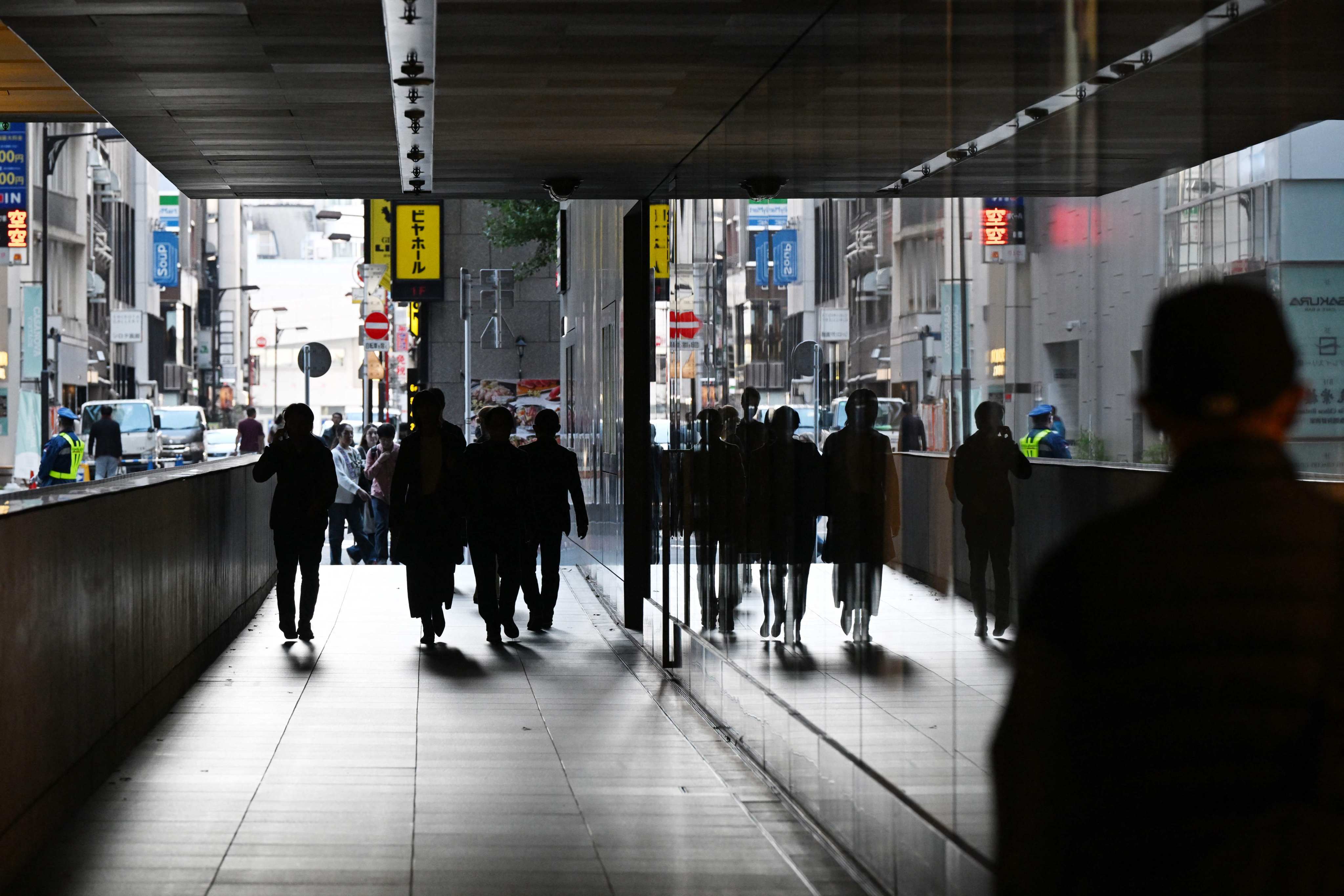 People walk between buildings in Tokyo on November 17. A diplomatic feud between China and Japan is having economic implications. Photo: AFP