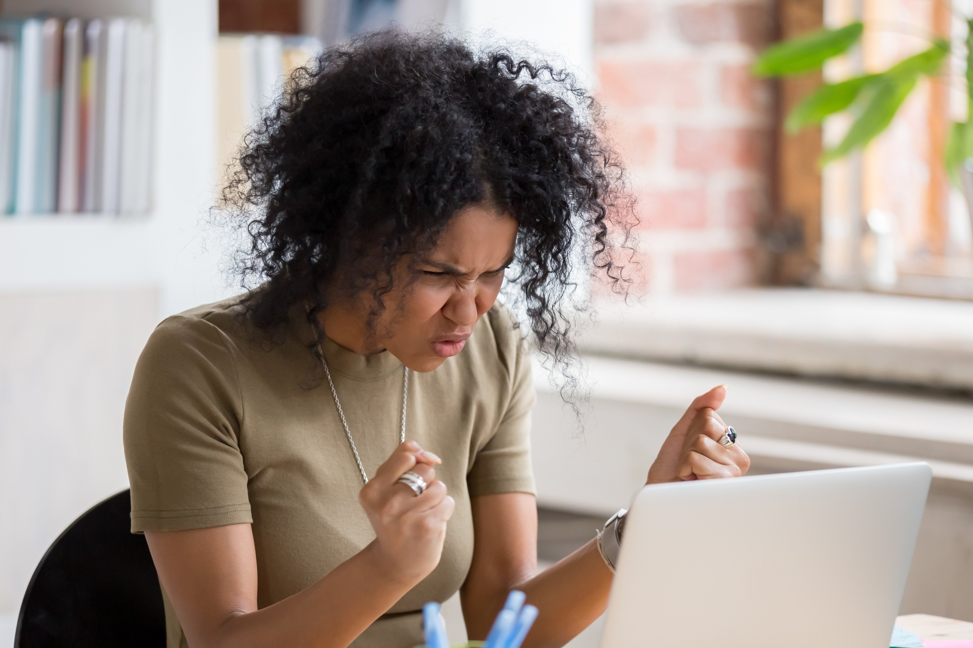 A woman angrily gestures at her laptop, highlighting the negativity of social media, where “rage bait” has become widespread. Photo: Shutterstock