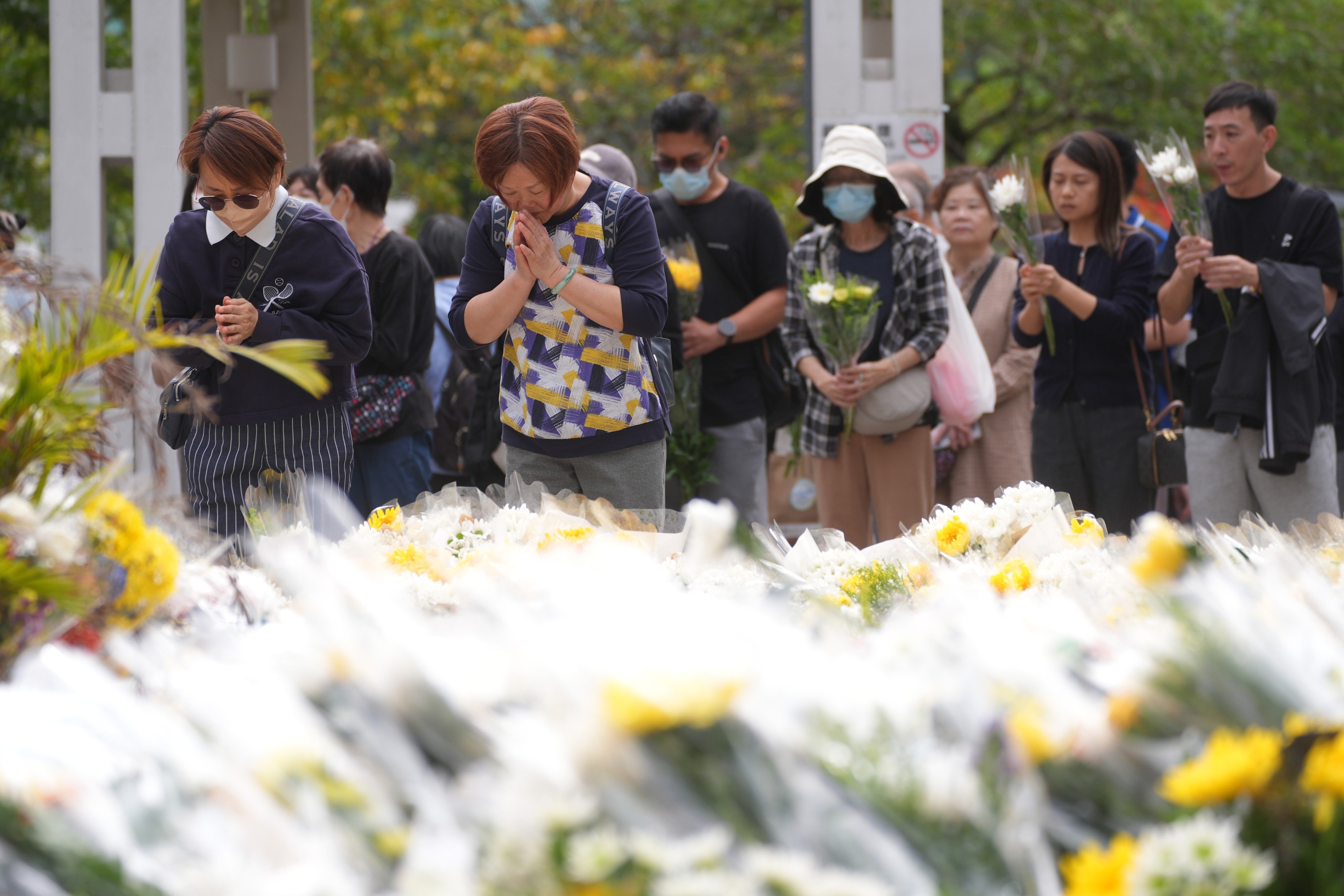 People arrive at the Kwong Fuk sitting-out area and lay flowers to mourn the victims and pay tribute to the affected residents in the Wang Fuk Court fire tragedy on Monday. Photo: Elson Li