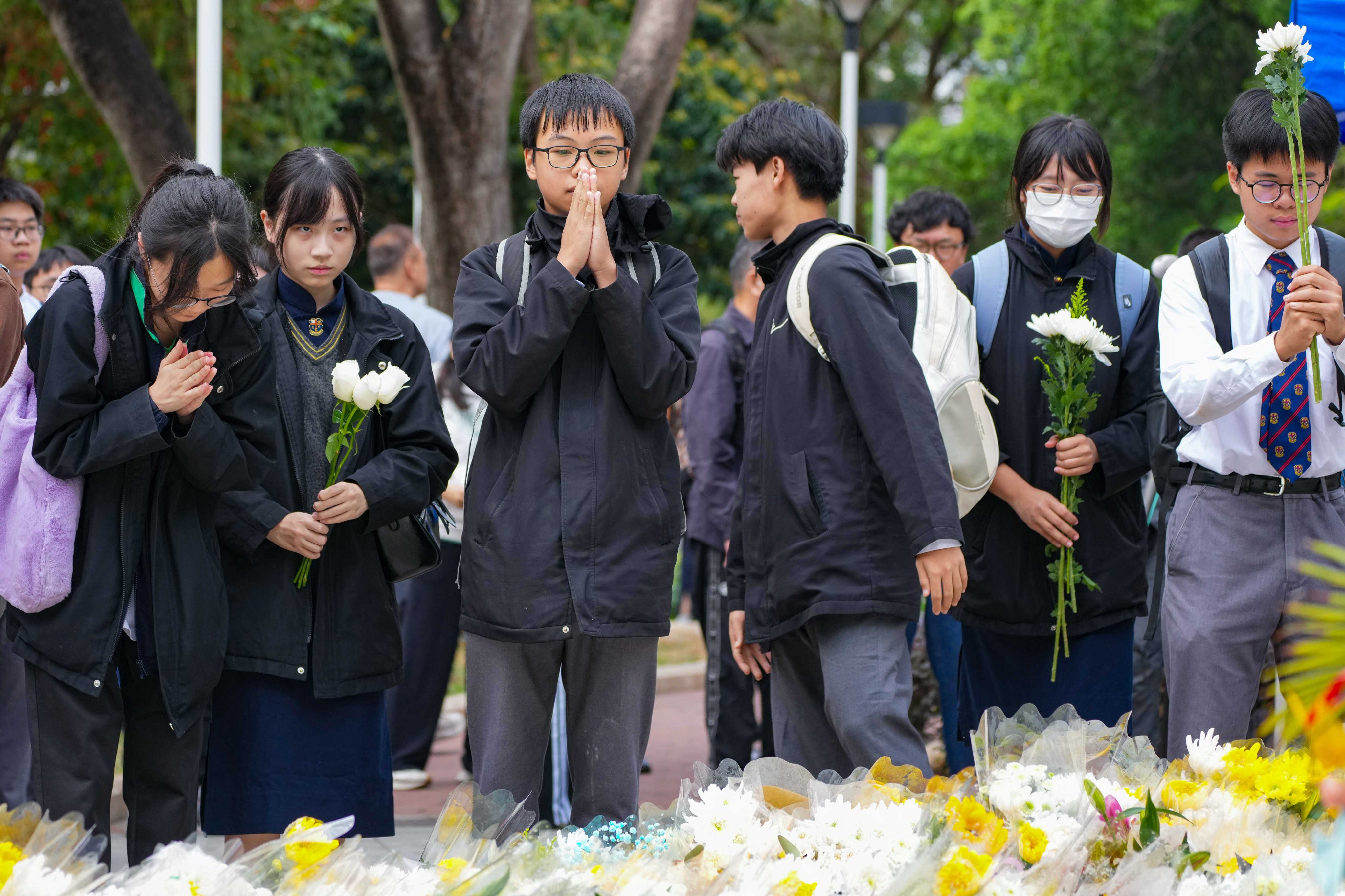 Grieving students offer prayers and flowers for the 151 blaze victims. Photo: Karma Lo