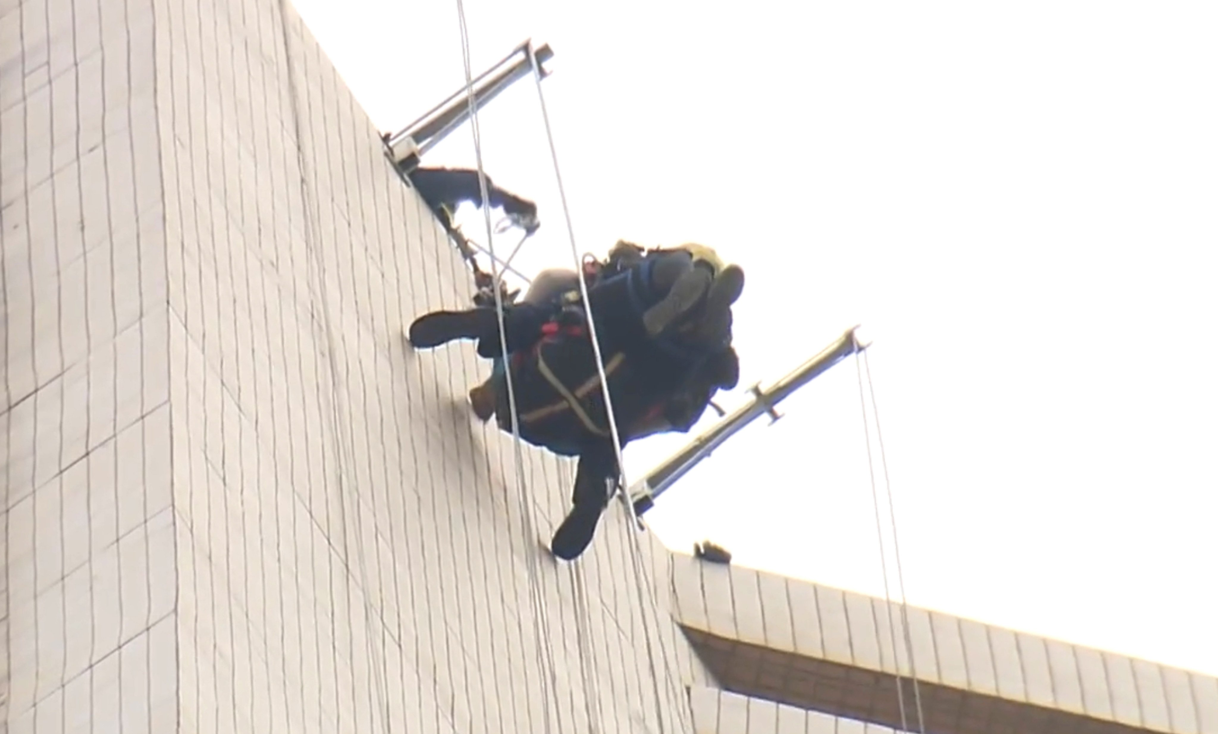 A firefighter abseils down to the gondola to rescue one of the workers. Photo: Now TV News