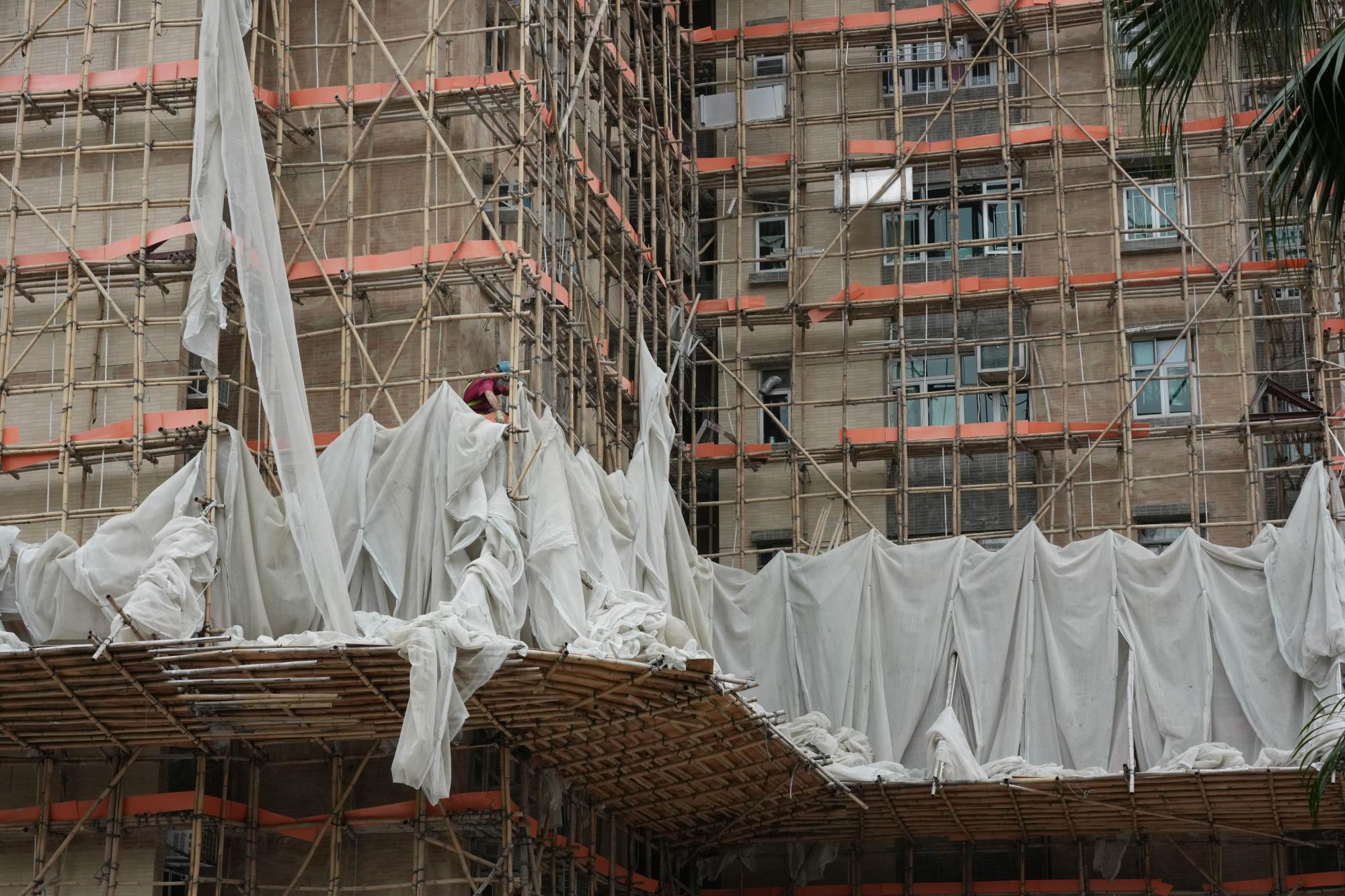 Workers remove the scaffolding mesh at Yee Kok Court in Cheung Sha Wan. Photo: Jelly Tse Workers remove the scaffolding mesh at Yee Kok Court in Cheung Sha Wan. Photo: Jelly Tse