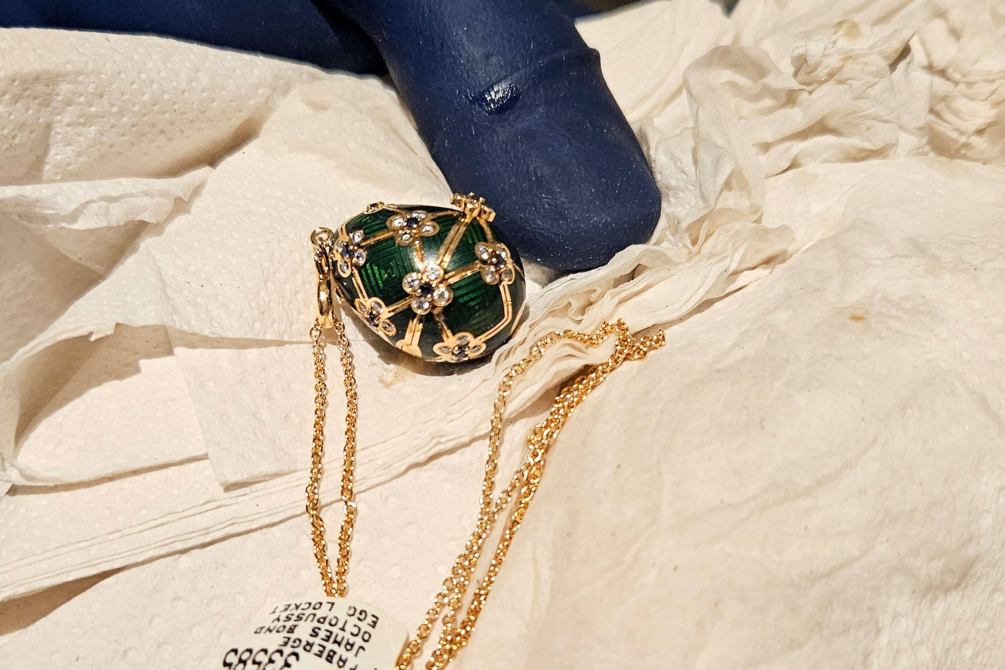 An officer displays a recovered diamond-encrusted green Faberge egg on Friday in Auckland, New Zealand after keeping a six-day watch over the thief accused of swallowing it. Photo: New Zealand Police/AFP