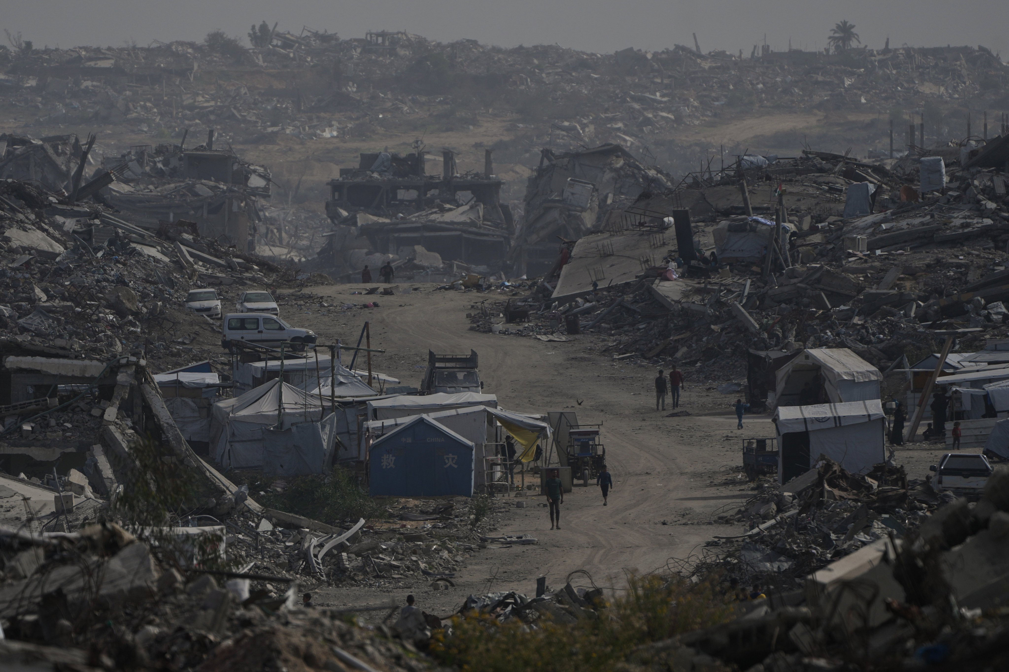 Palestinians walk through the destruction left by the Israeli air and ground offensive in Gaza City, Friday. Photo: AP